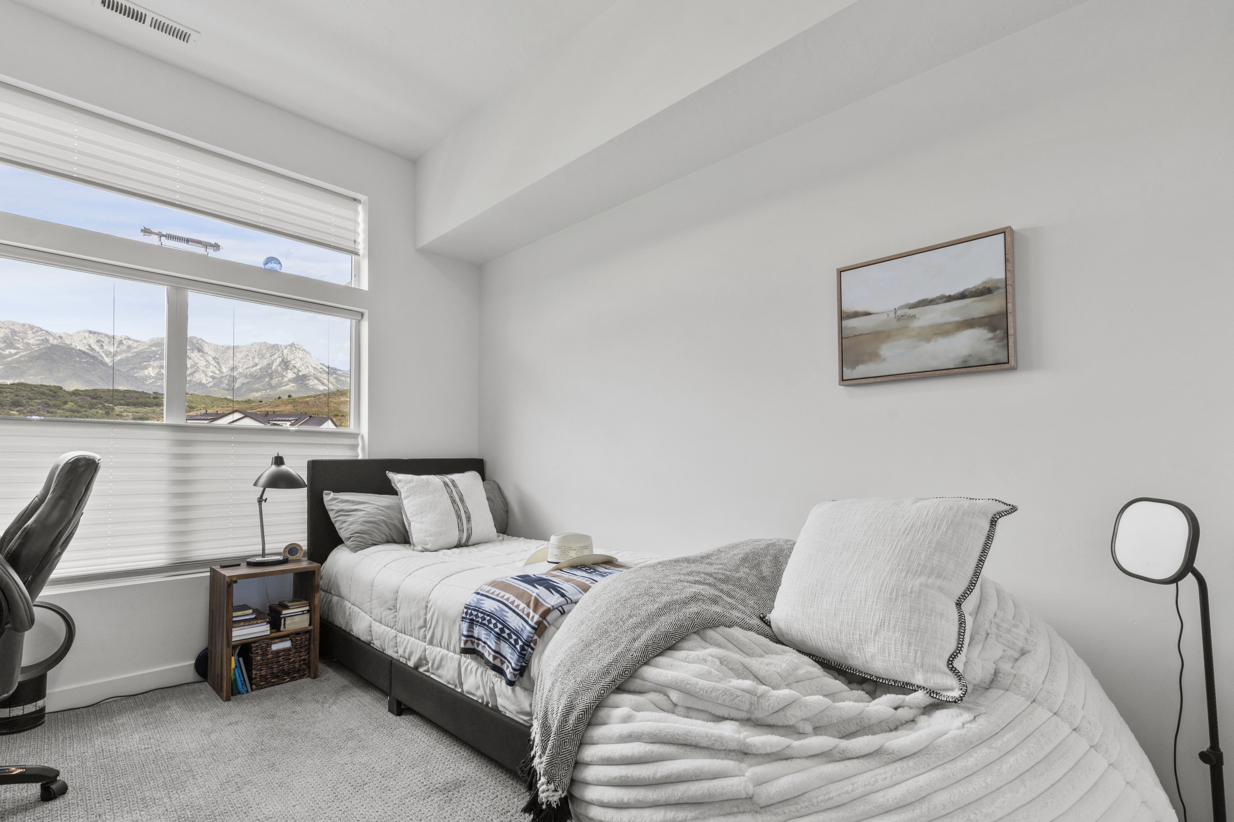 Spacious room featuring broad windows with mountain scenery, a white color palette, and light gray carpeting