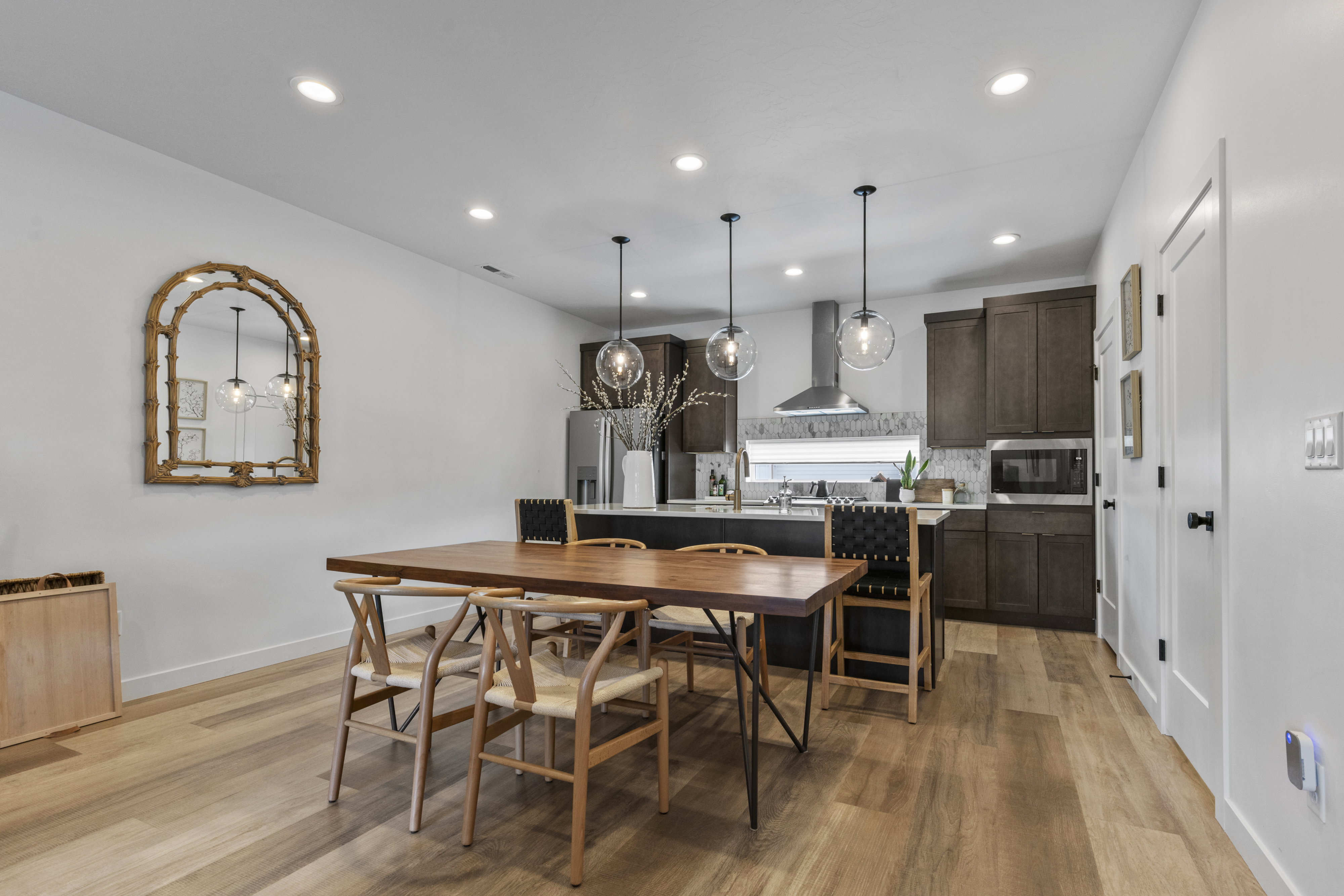 Open-concept dining area featuring wood-finish flooring, recessed lighting, and a kitchen with dark cabinetry