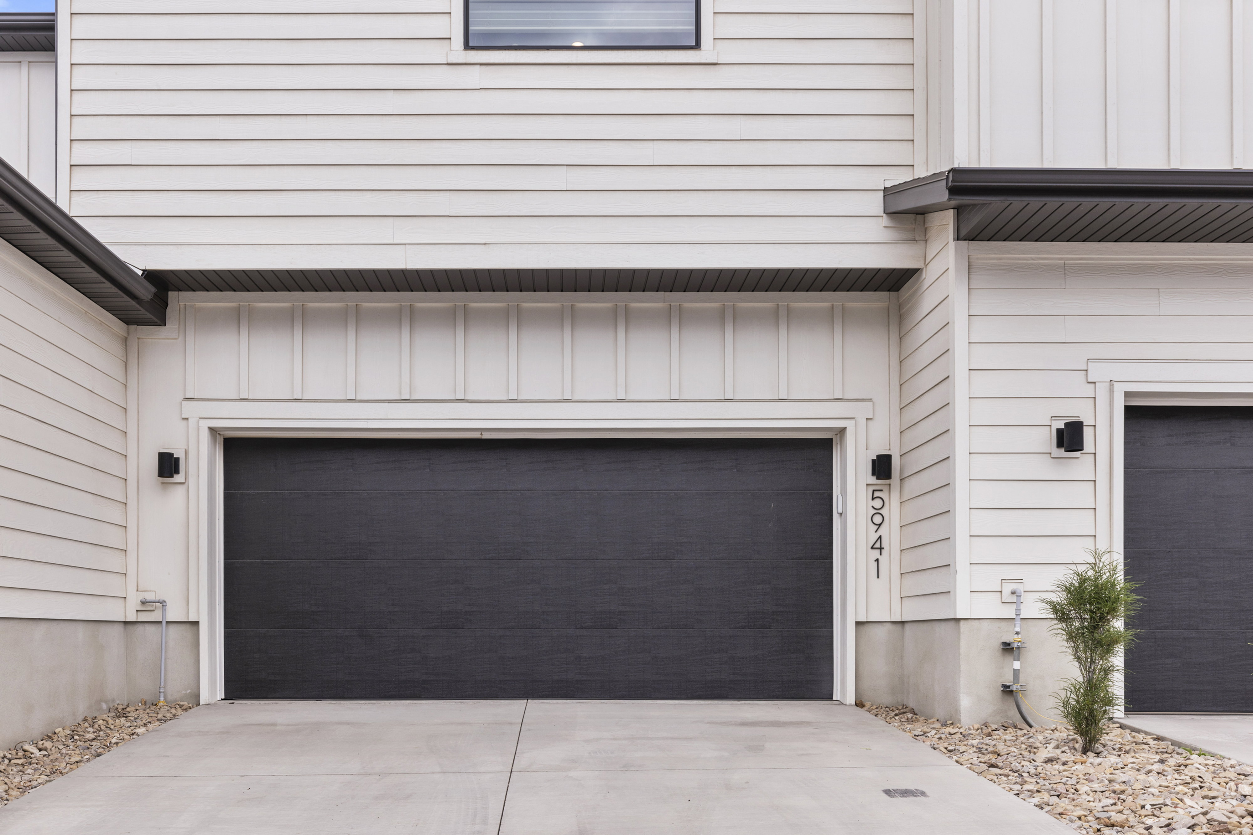 White horizontal siding exterior with contrasting black garage doors