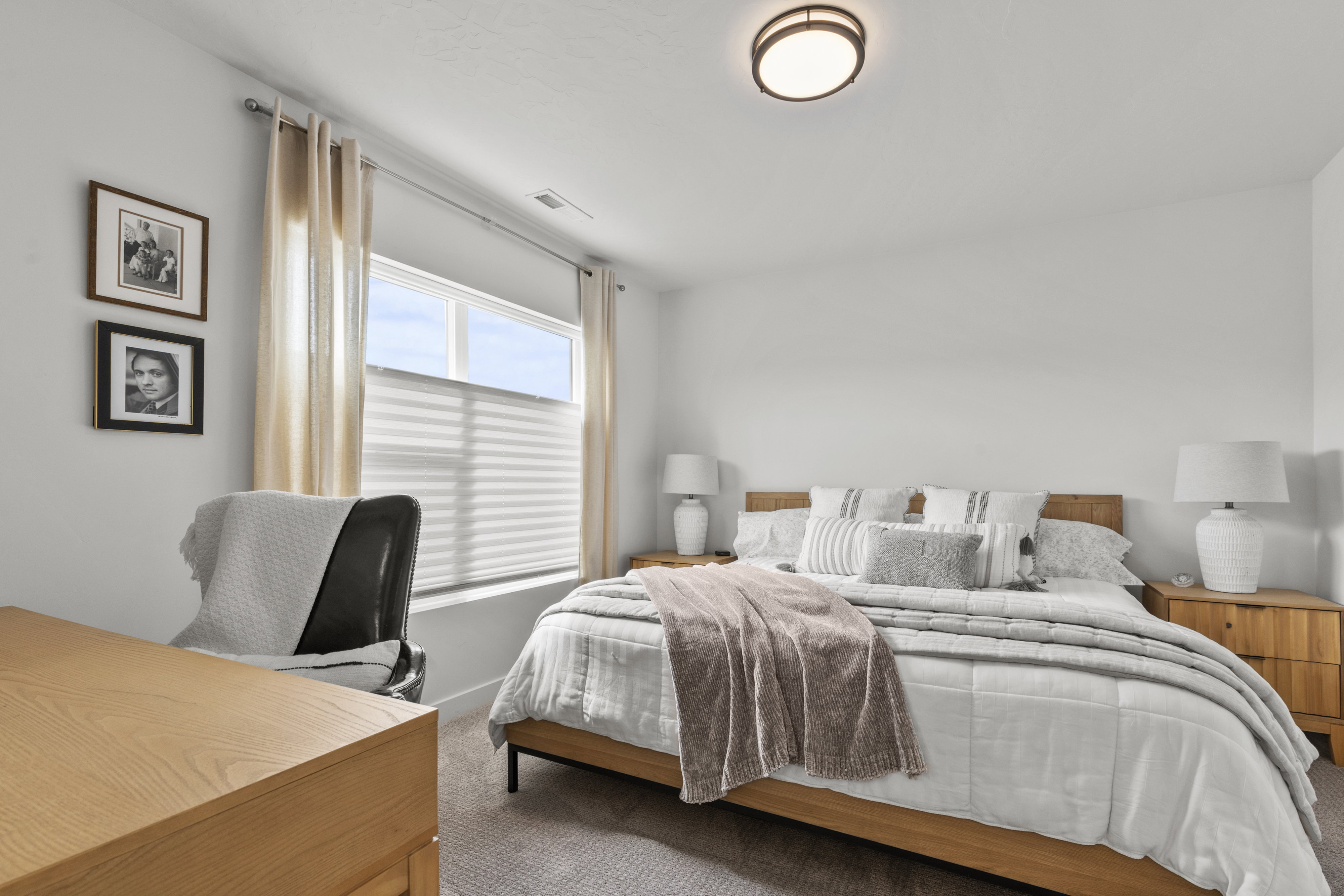 Bedroom featuring a large window with cellular blinds, a ceiling-mounted light fixture, and neutral-toned carpeting