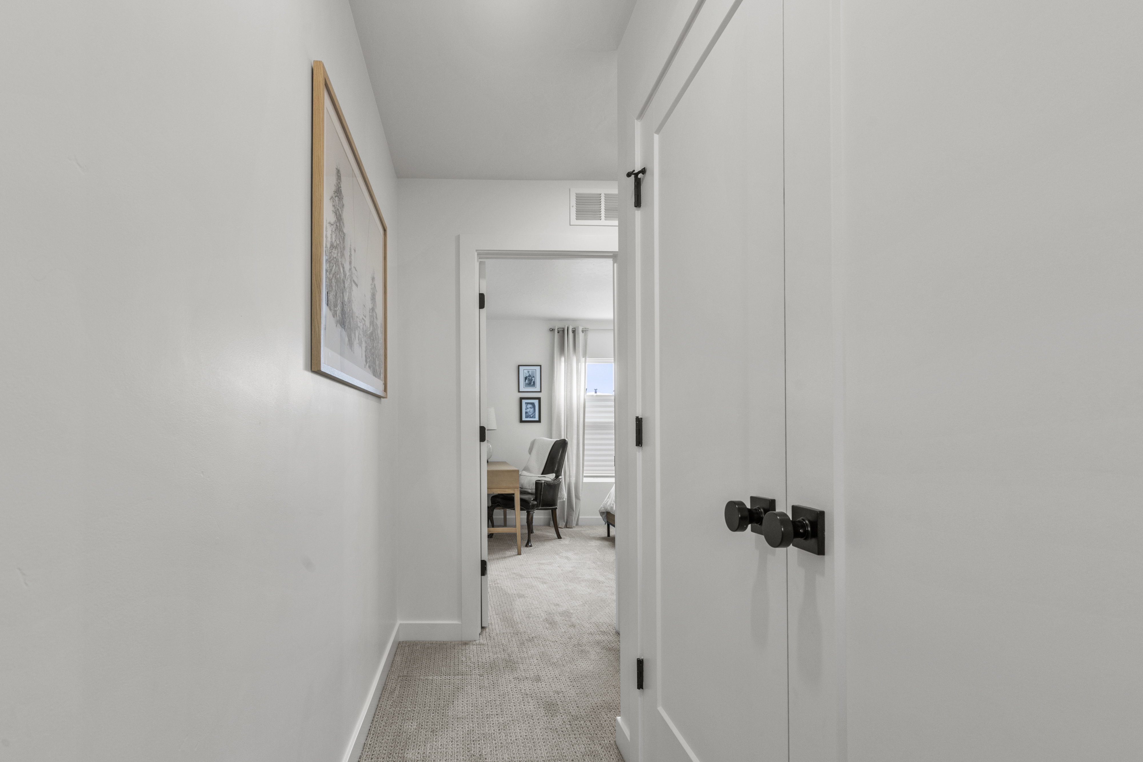 White interior walls featuring a framed art piece, white trim, and light-colored carpet flooring