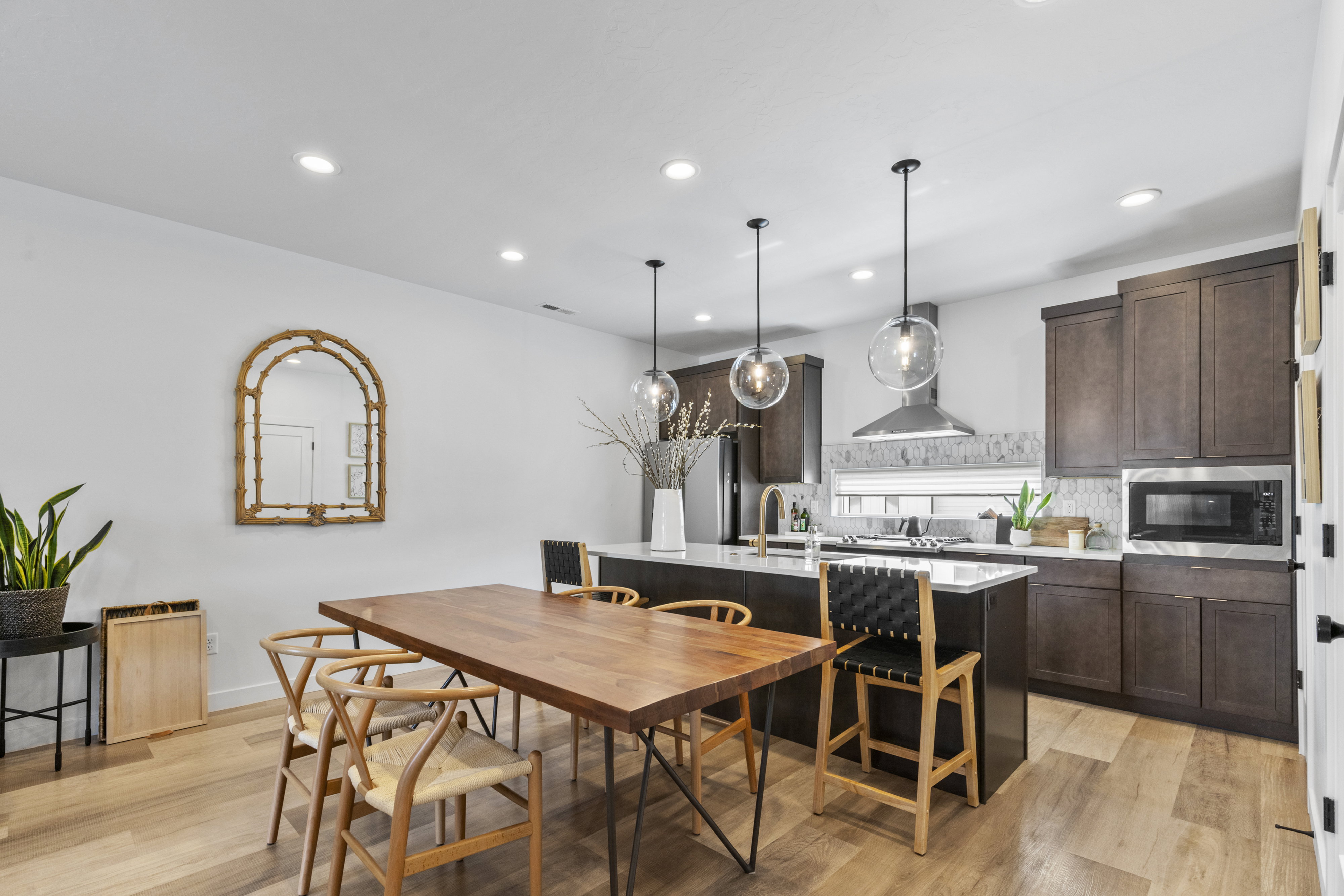 Open-concept kitchen and dining area featuring light wood-finish flooring, recessed lighting, and a modern kitchen island with pendant lighting