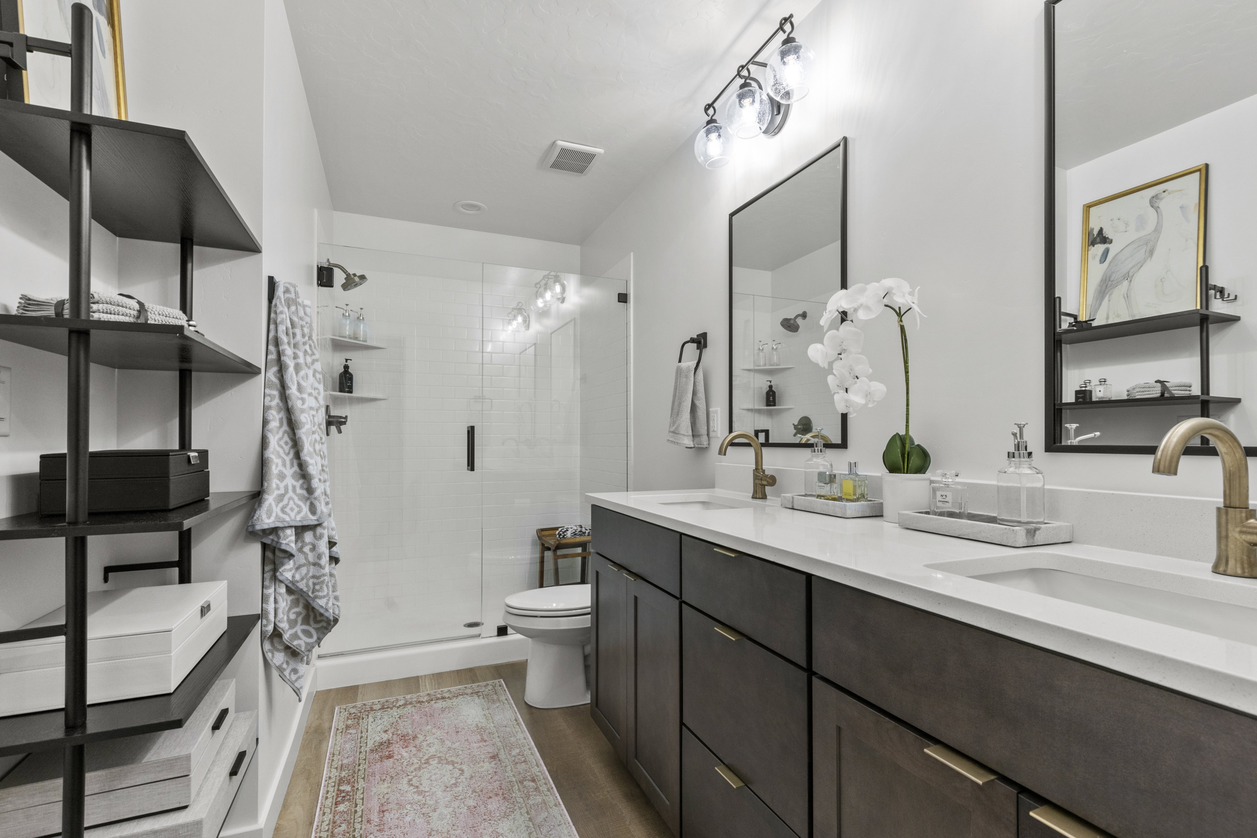 Contemporary bathroom featuring a double vanity with dark wood-finish cabinetry, white countertops, and brass-tone fixtures
