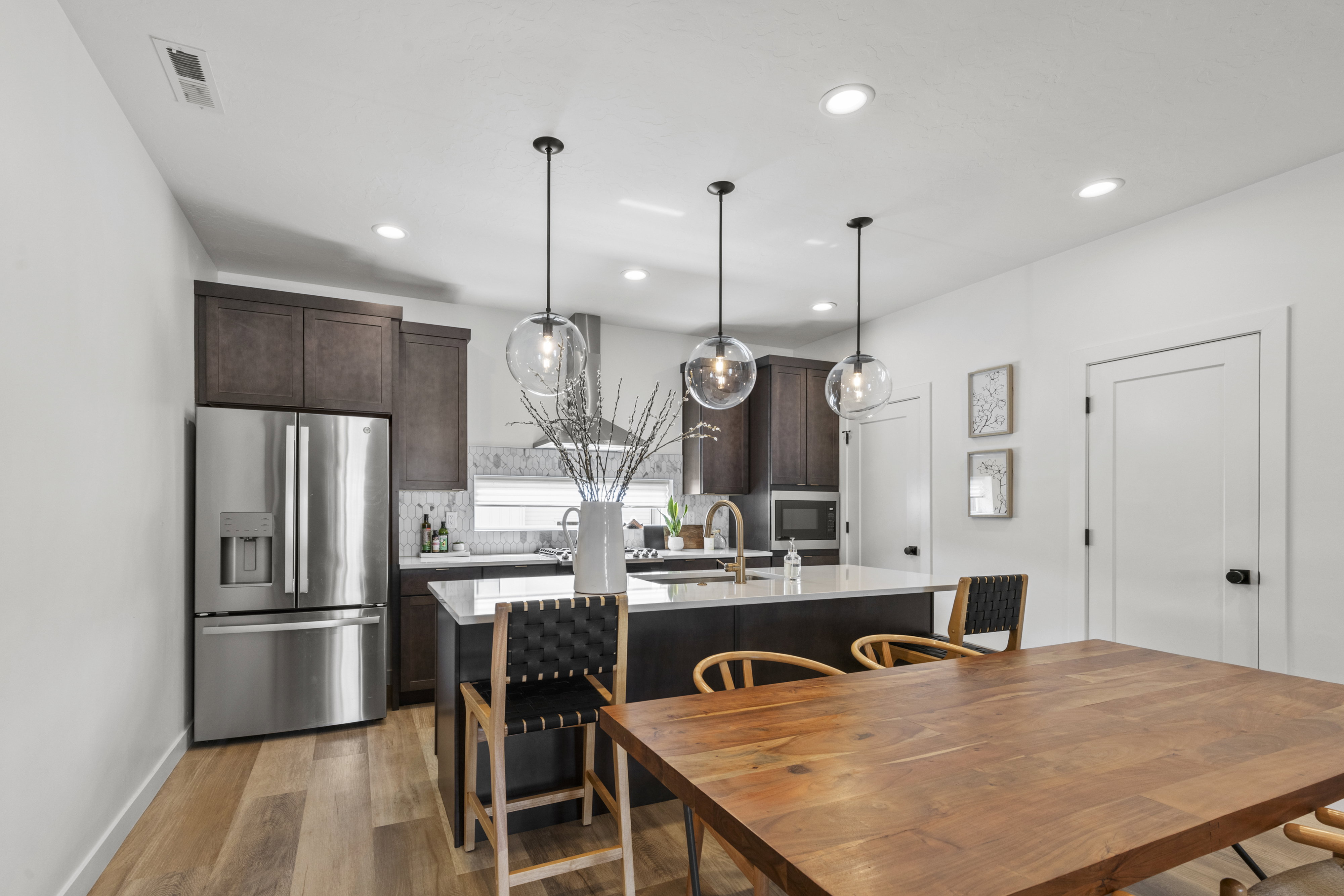 Modern kitchen featuring dark wood cabinetry, a center island with countertop seating, stainless steel appliances, and wood-finish flooring