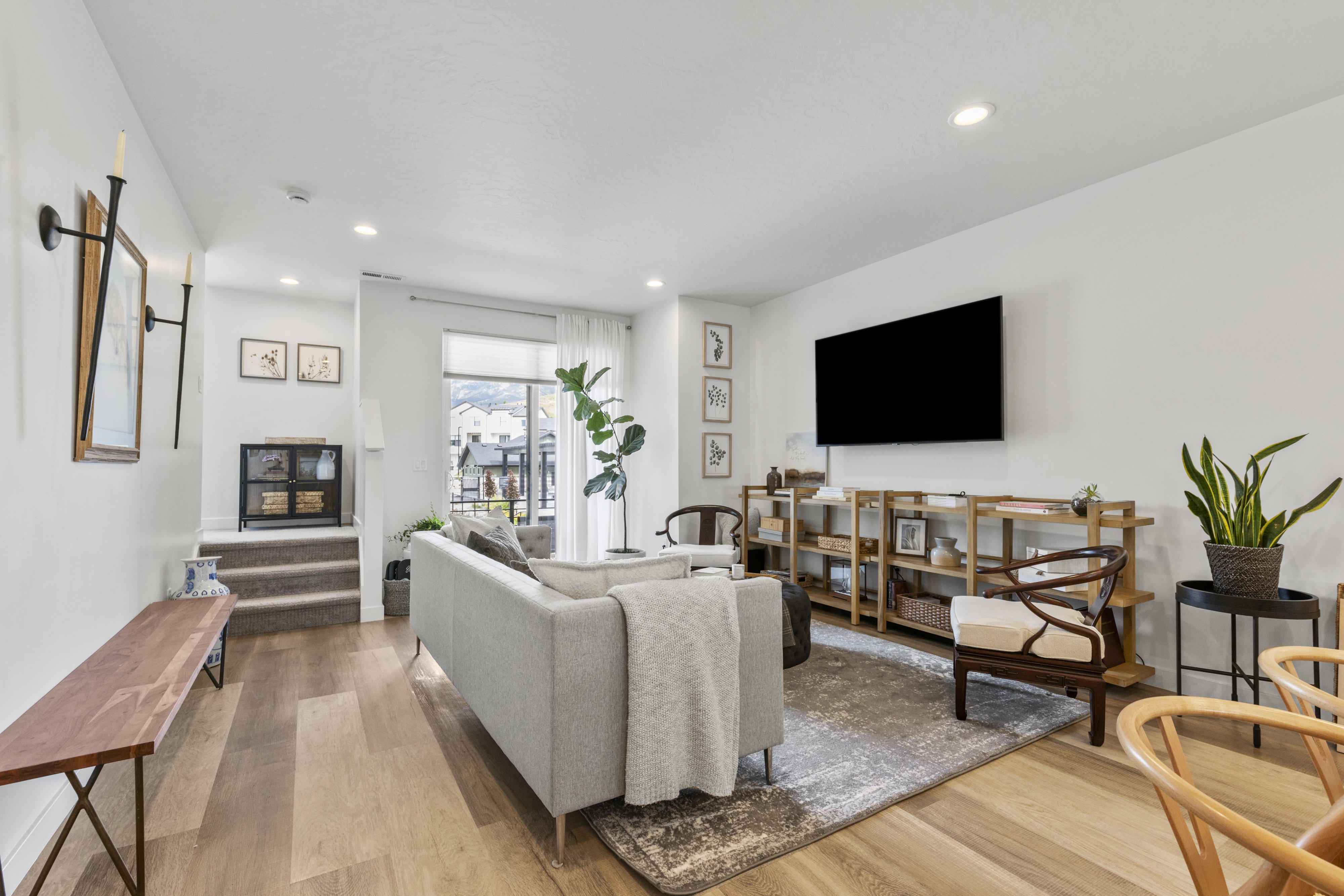 Bright living space featuring wood-finish flooring, recessed lighting, and a large window with white blinds