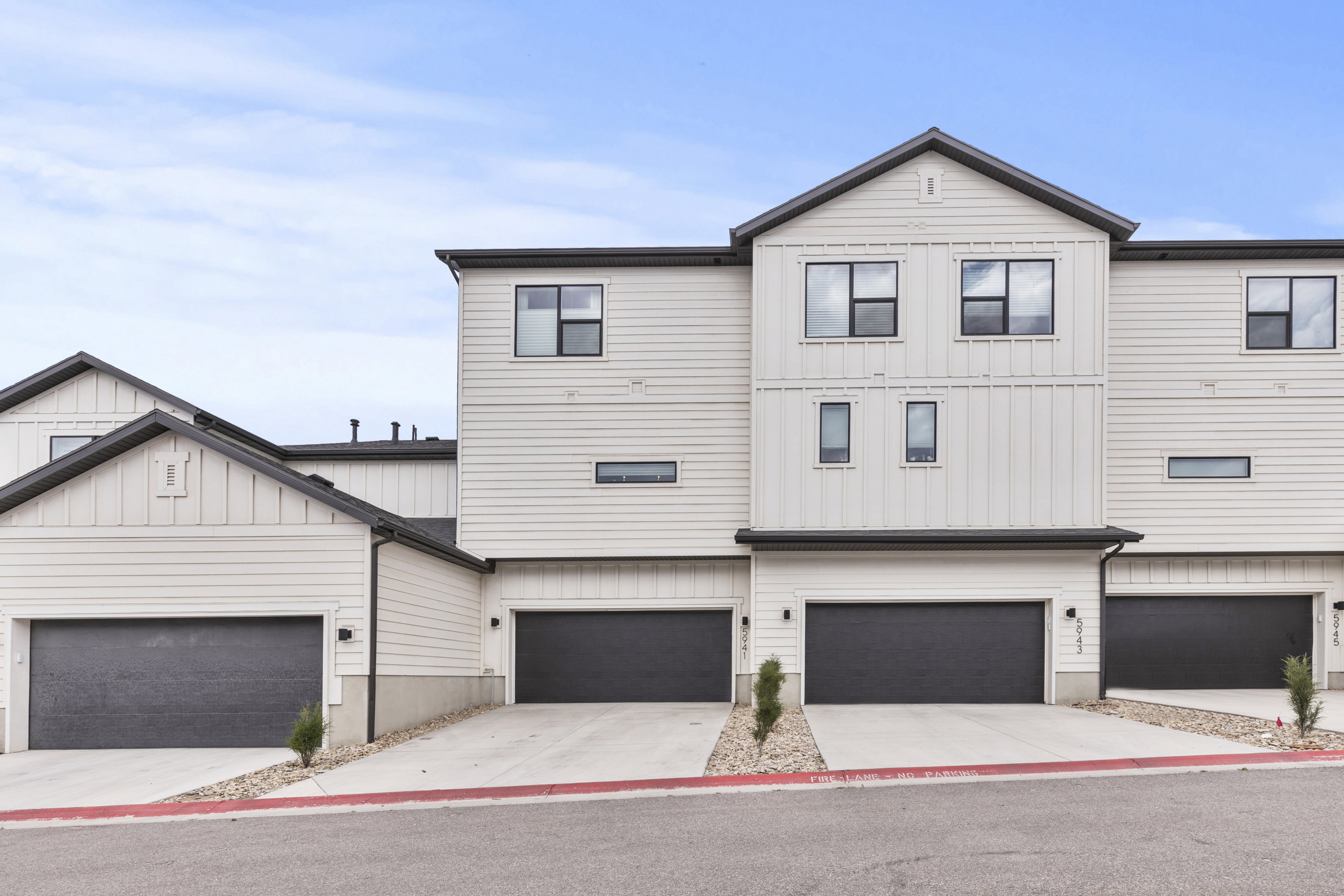 Modern townhome exterior featuring light-colored horizontal siding and vertical accents