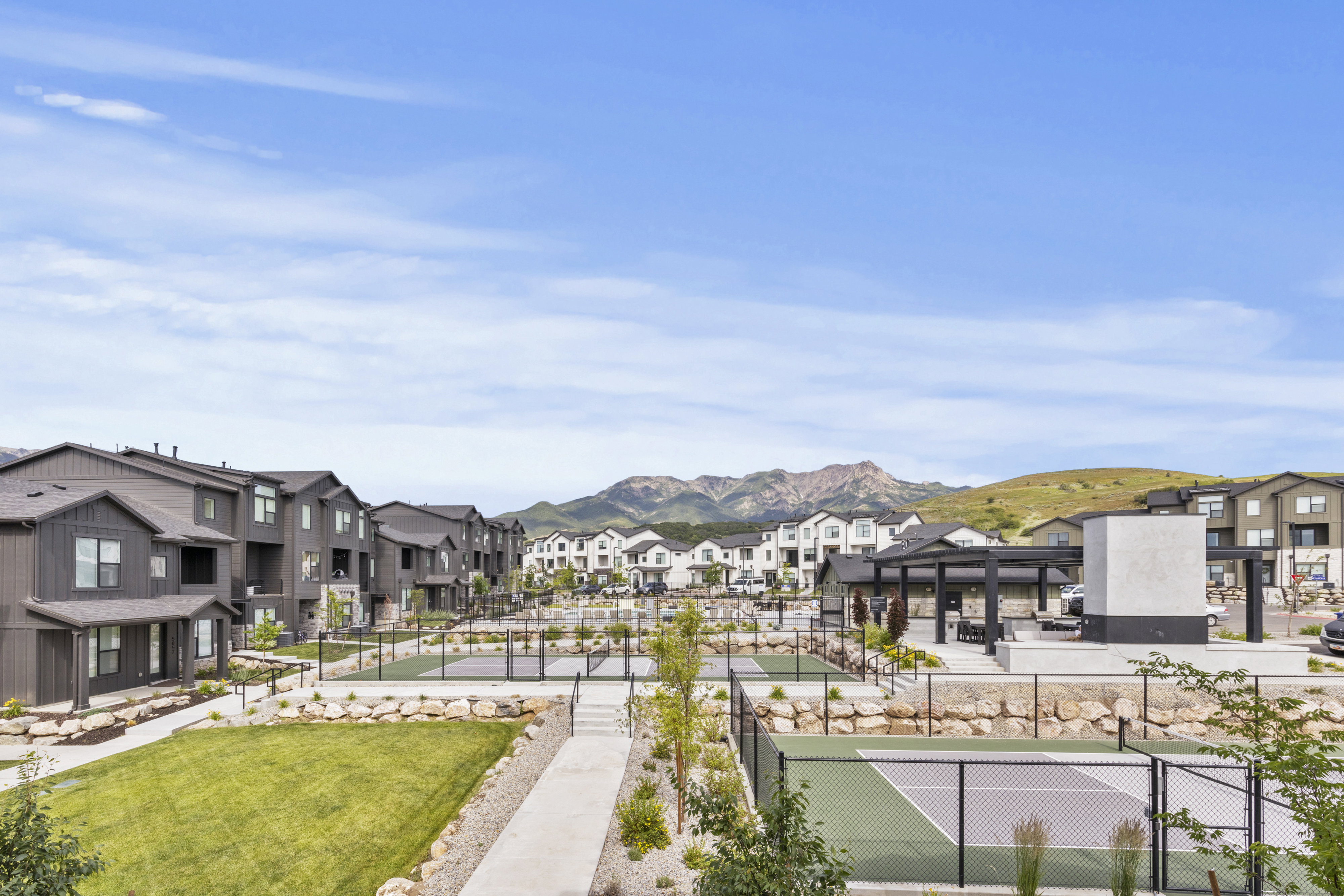 Community landscape featuring multiple multi-story residential buildings, paved pathways, and green spaces