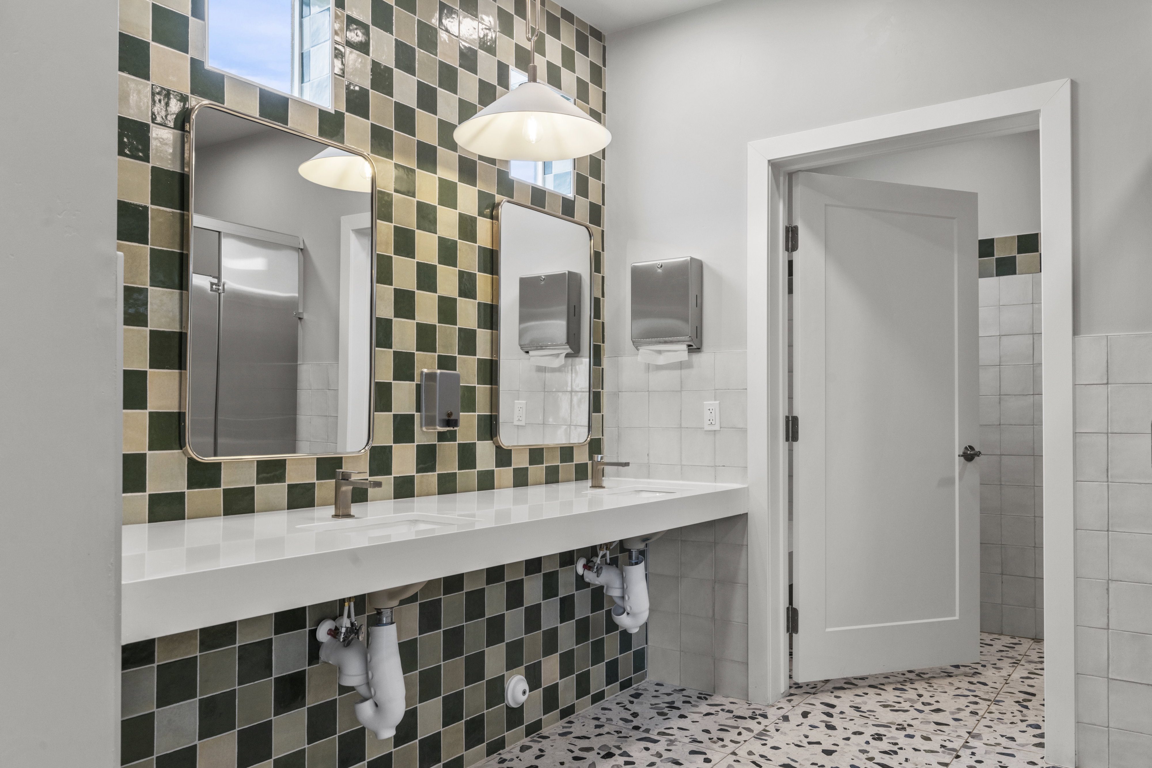 Bathroom featuring dual white rectangular sinks with bronze-finish faucets, set within a white countertop