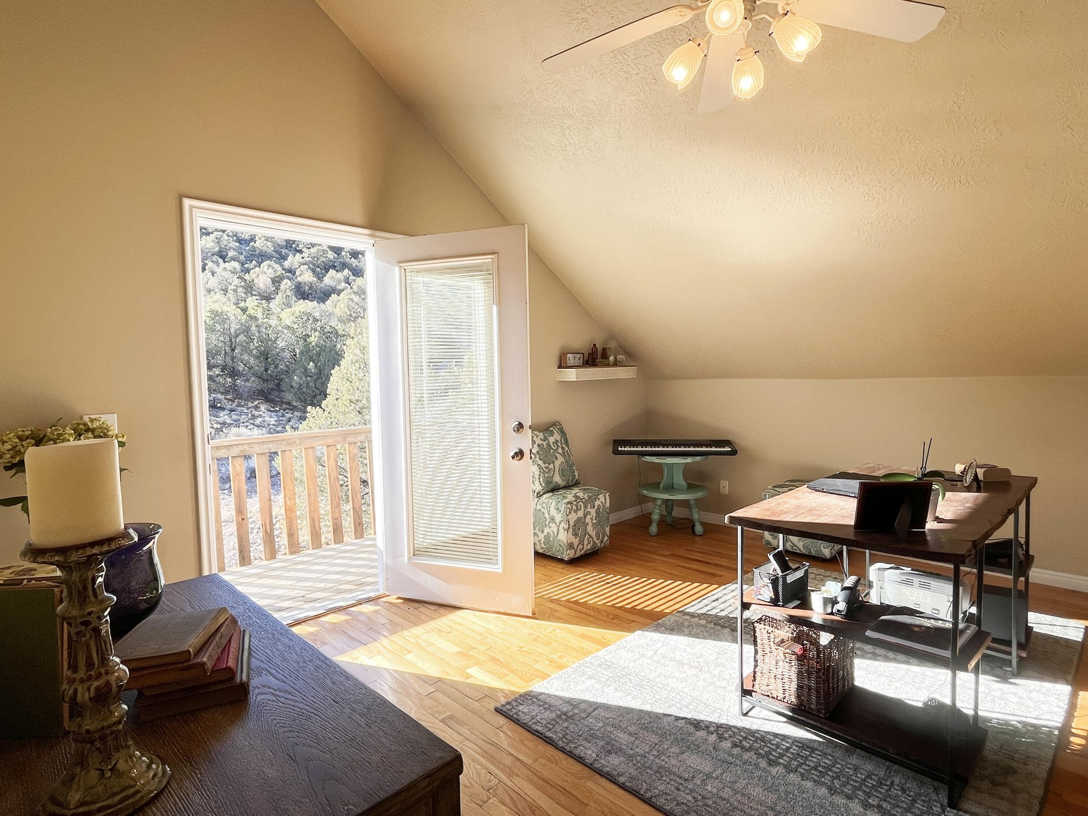 Room featuring wood-finish flooring, a ceiling fan with integrated lighting, and a sloped ceiling design