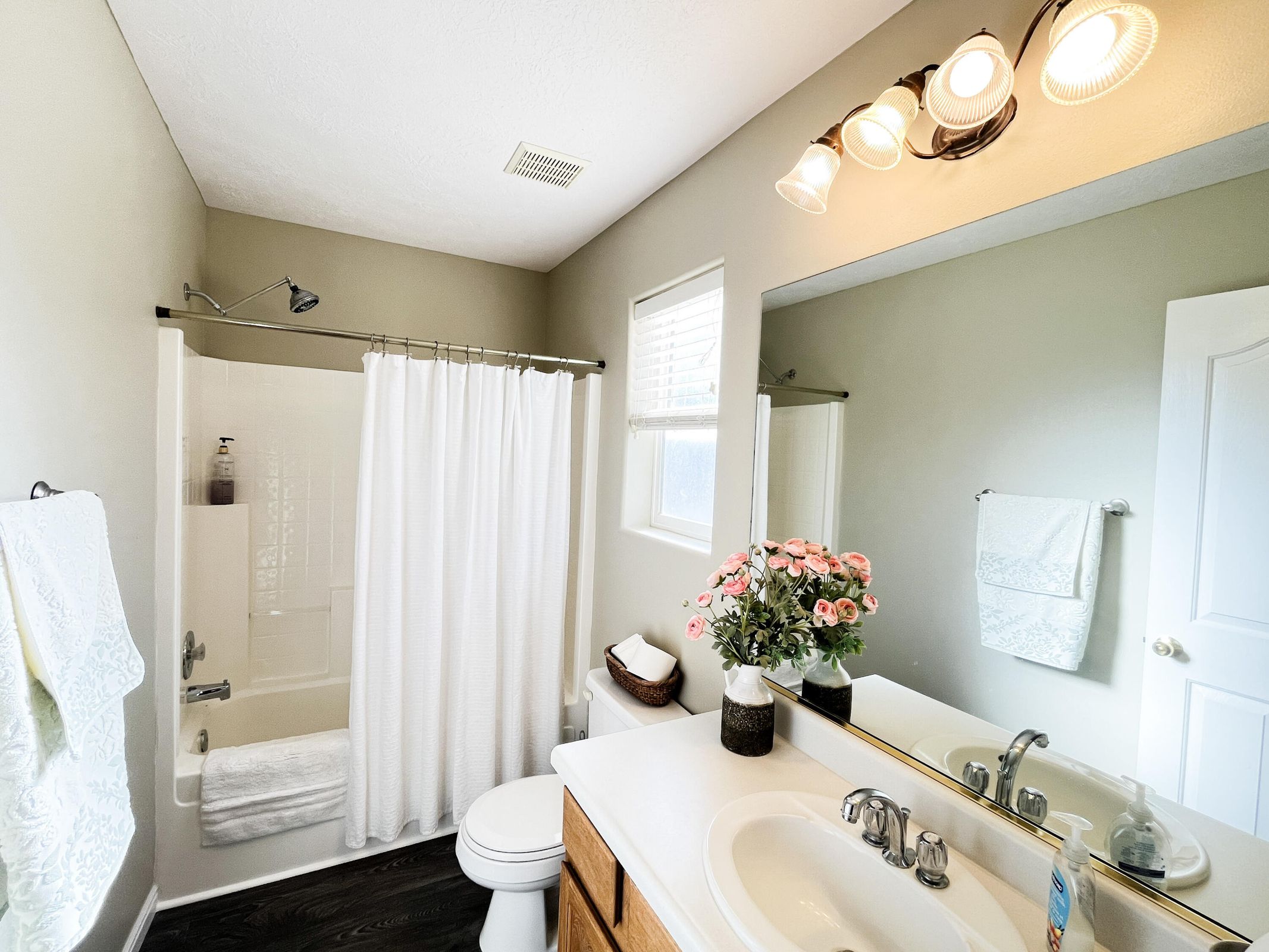 Full bathroom featuring a white tub/shower combination, white toilet, and dark wood-finish flooring