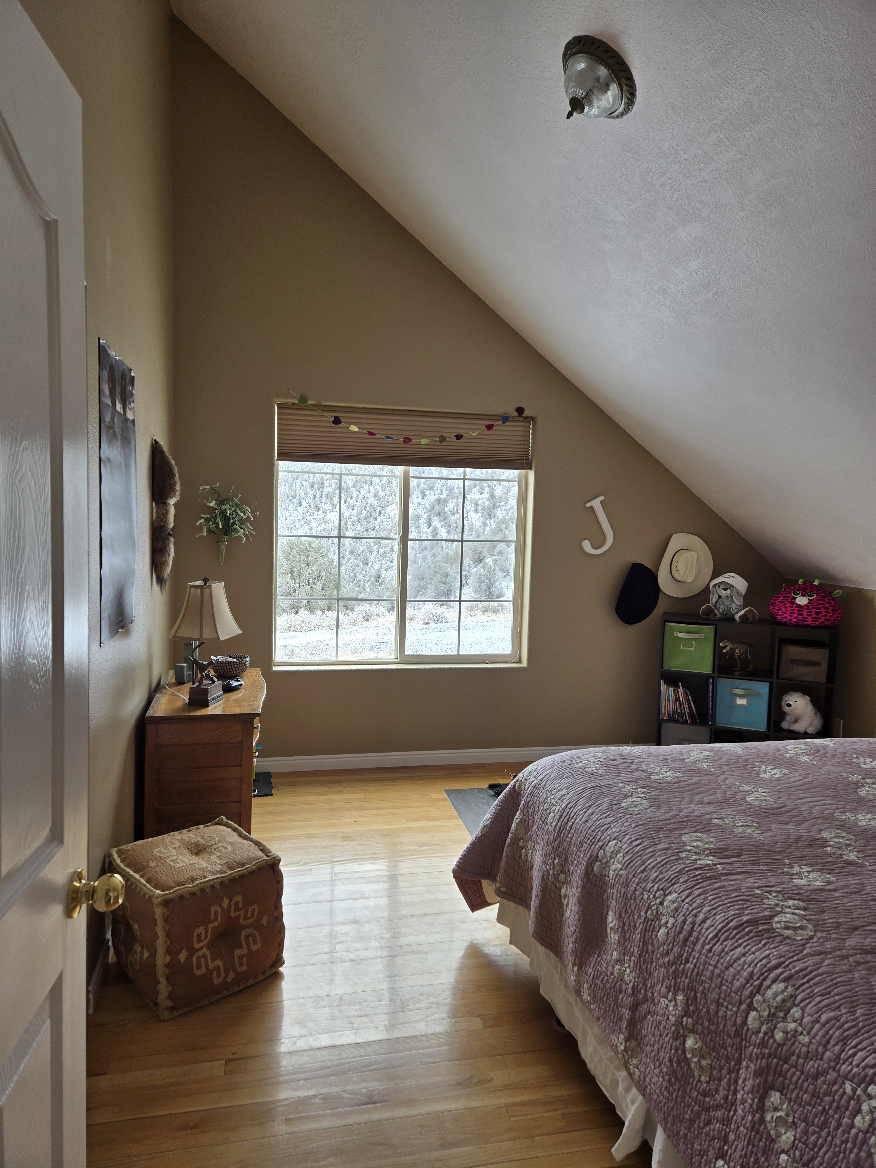Room featuring sloped ceilings, a window with horizontal blinds, and wood-finish flooring