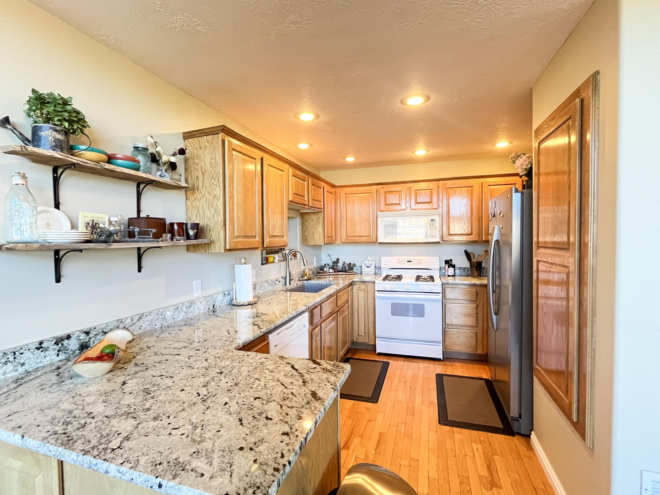Kitchen featuring light wood cabinetry and light-toned granite-style countertops