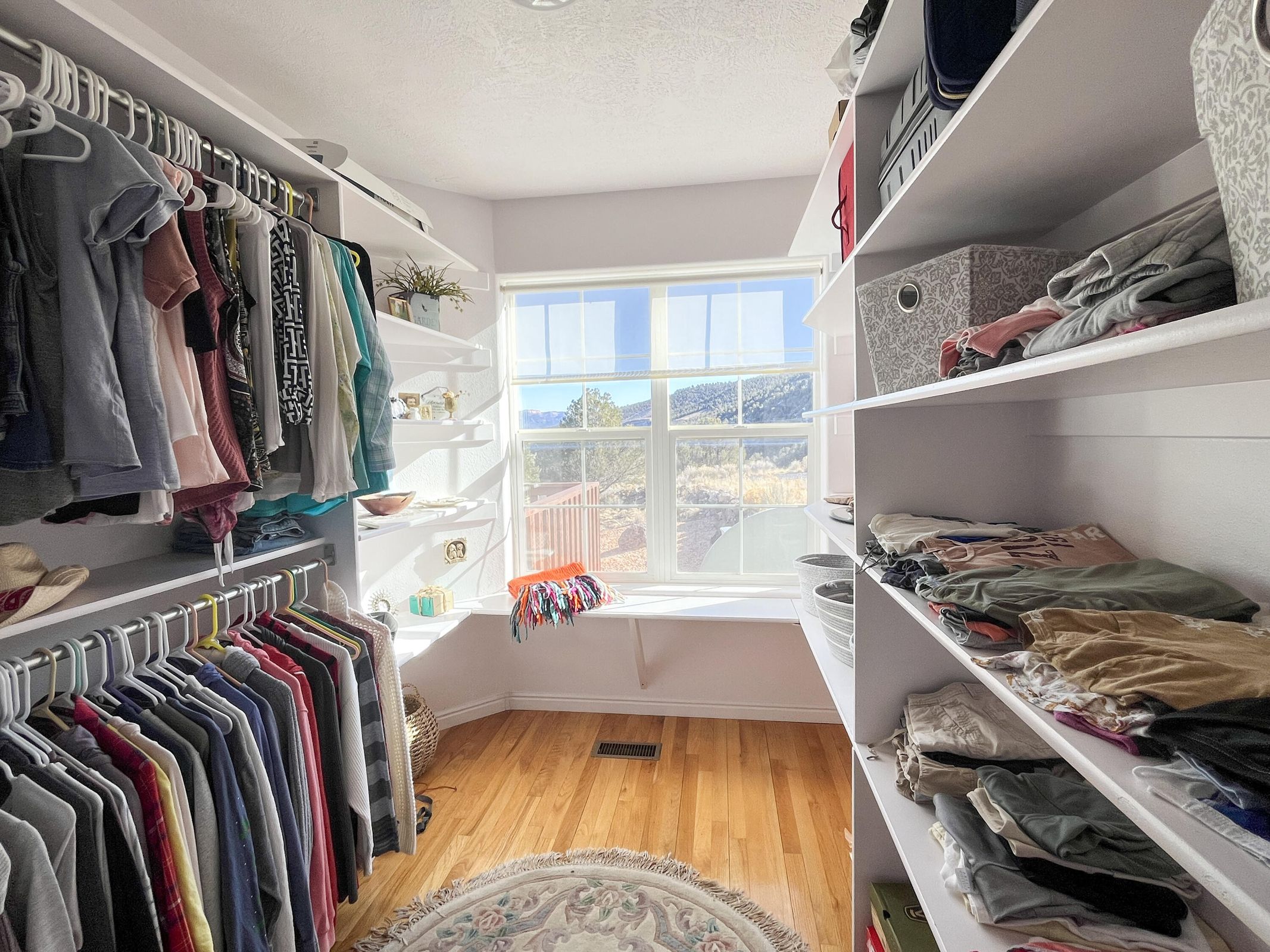 Custom walk-in closet featuring extensive built-in shelving, hanging rods, and wood-finish flooring