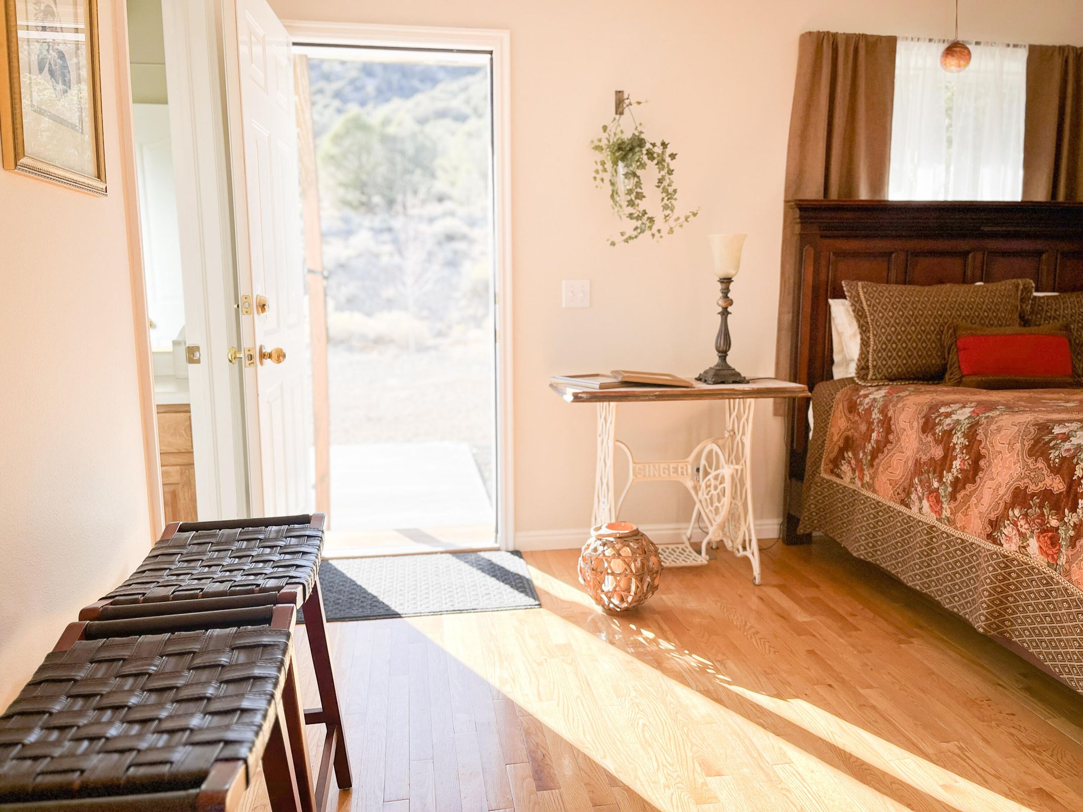 Hardwood flooring throughout featuring an exterior door with brass hardware, a dark wood headboard, and light-toned walls