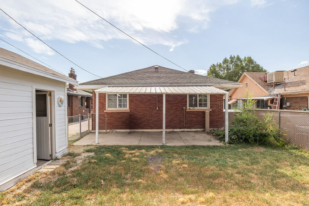 Red brick exterior featuring a covered patio, concrete pad, and vinyl siding shed