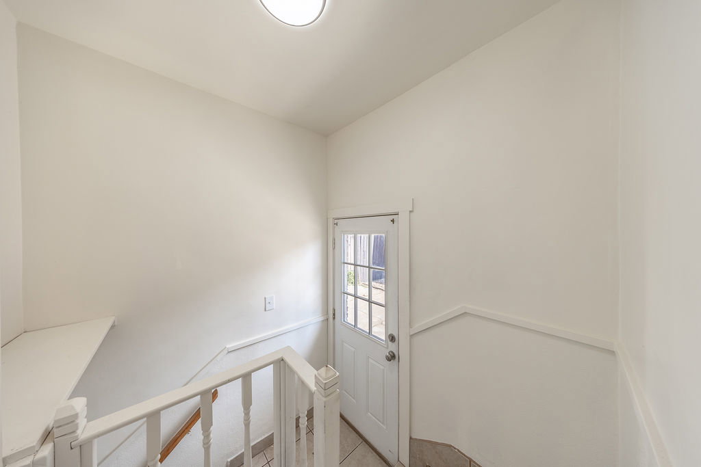 Interior stairway featuring white balusters and a wood-finish handrail