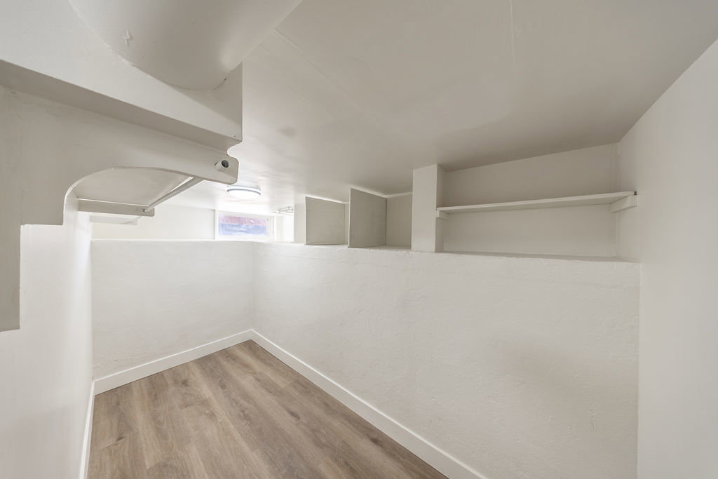Storage area featuring wood-finish flooring and bright white walls