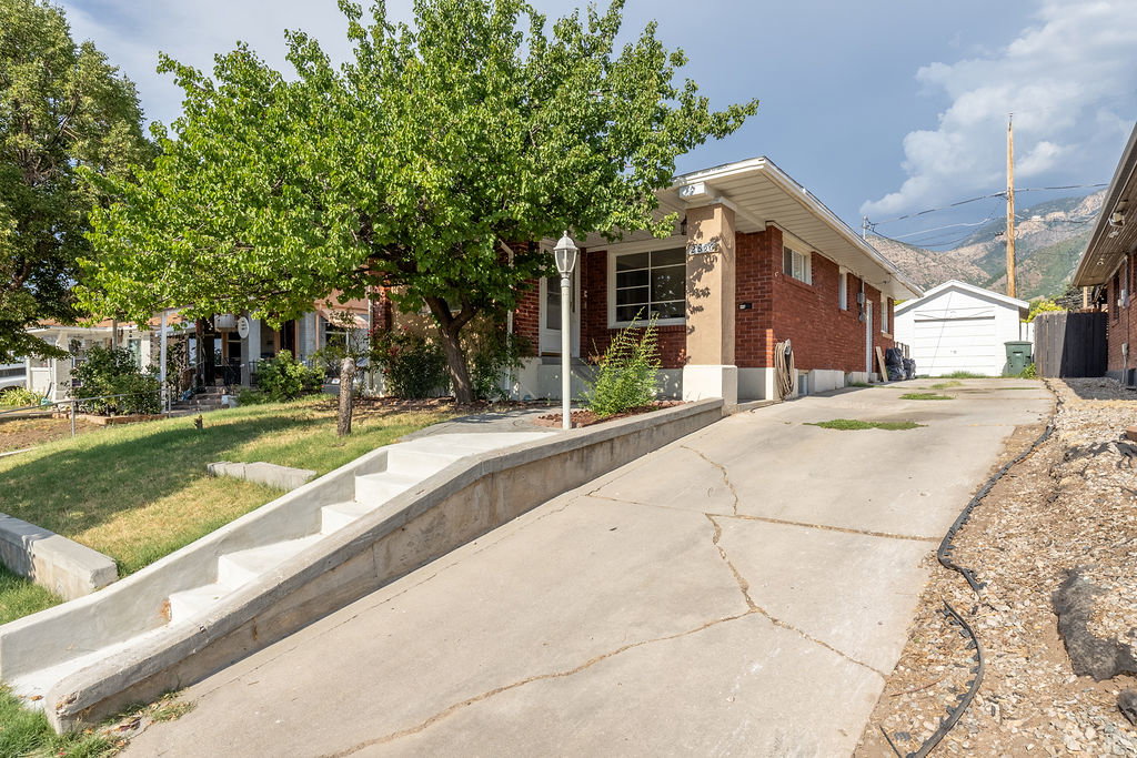 Brick exterior with white trim, concrete driveway, and a separate garage structure