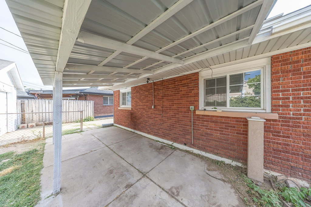 Covered carport with concrete flooring and a corrugated metal roof