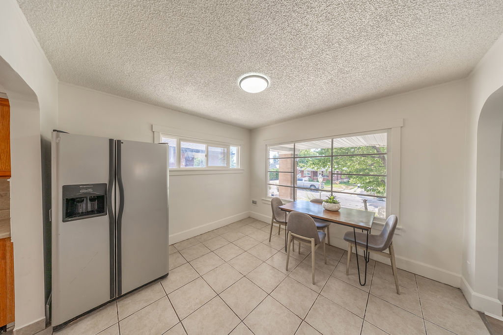 Spacious room featuring tile flooring, a large window, and a built-in side-by-side refrigerator with dispenser