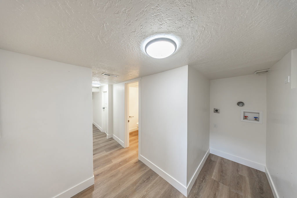 Dedicated laundry area featuring hookups for washer and dryer, complemented by wood-finish flooring and crisp white walls