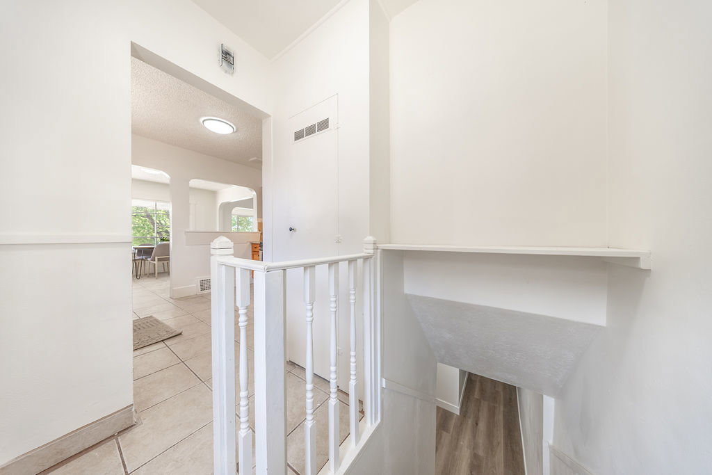 Open interior with white walls, a white spindle railing, and a tile floor