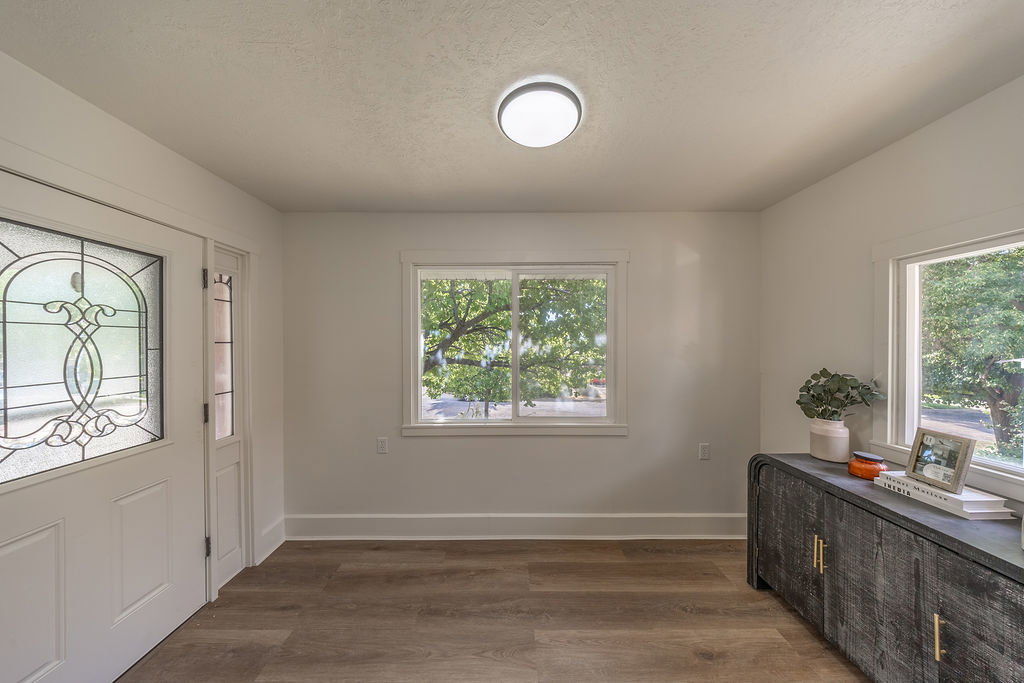 Entryway featuring a decorative glass panel front door, durable wood-finish flooring, and multiple windows