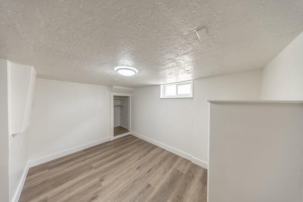 Room featuring wood-finish flooring, white walls, and a recessed window