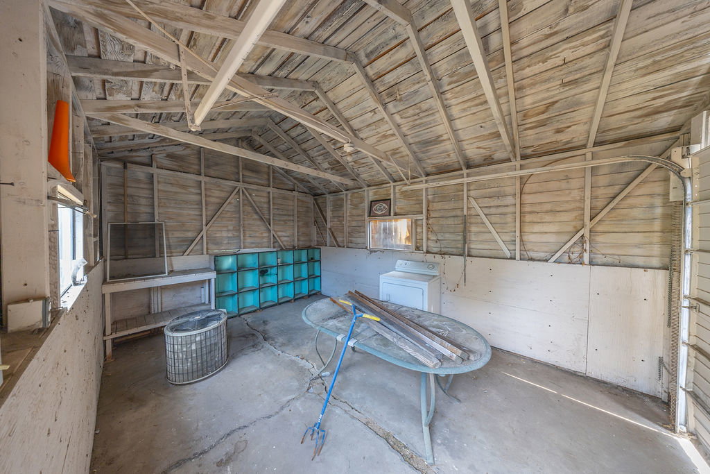 Detached structure featuring exposed beam ceiling, wood-plank walls, concrete flooring, and multiple windows