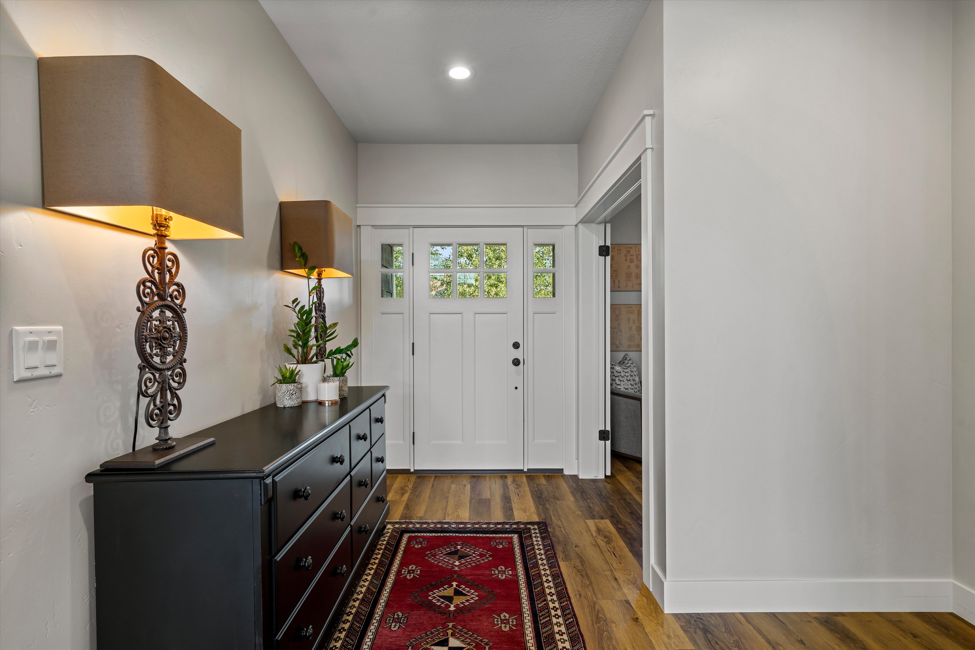 Entryway featuring wood-finish flooring, a white paneled entry door with sidelights, transom window, and an overhead recessed light