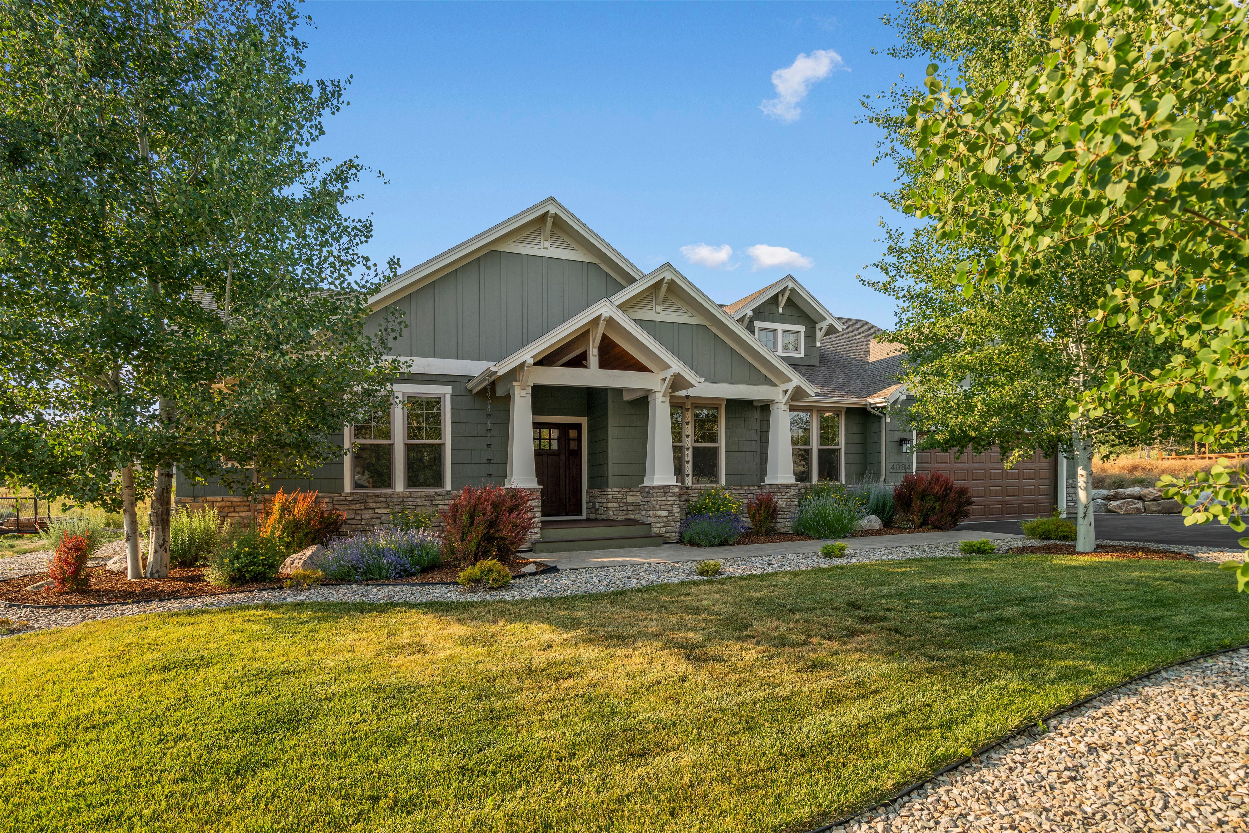 Craftsman-style residence featuring a prominent covered entry with stone columns and wood detailing