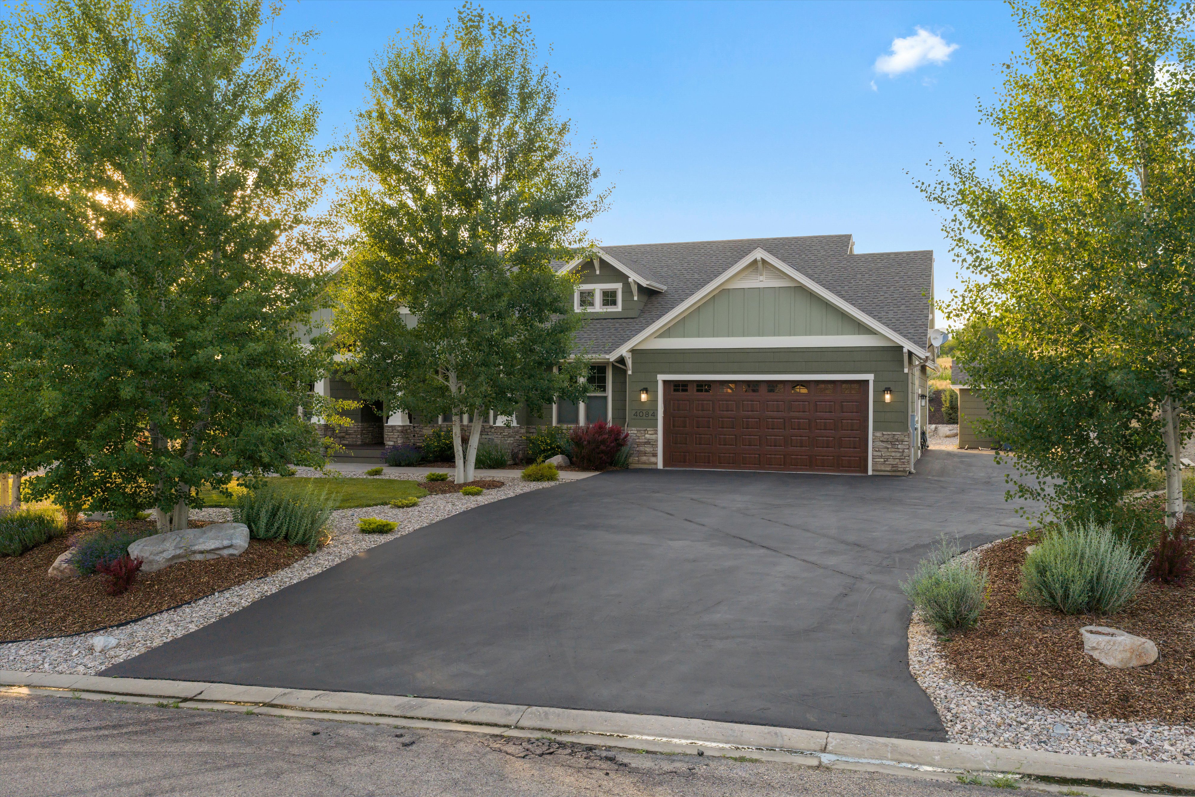 Single-family residence featuring a two-car garage with a paneled door, stone facade accents, and a shingle roof