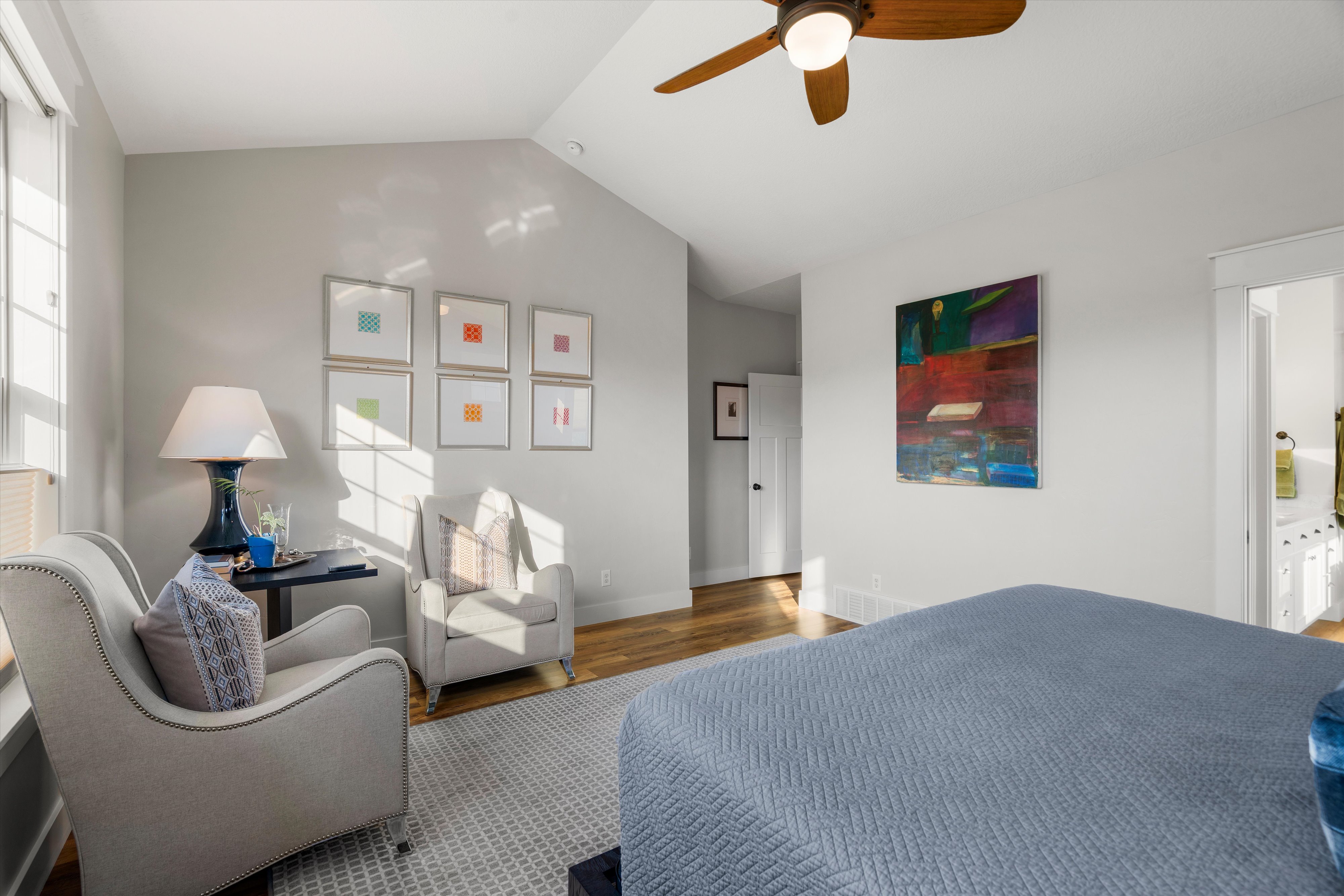 Spacious room featuring vaulted ceilings, wood-finish flooring, a ceiling fan, and multiple windows