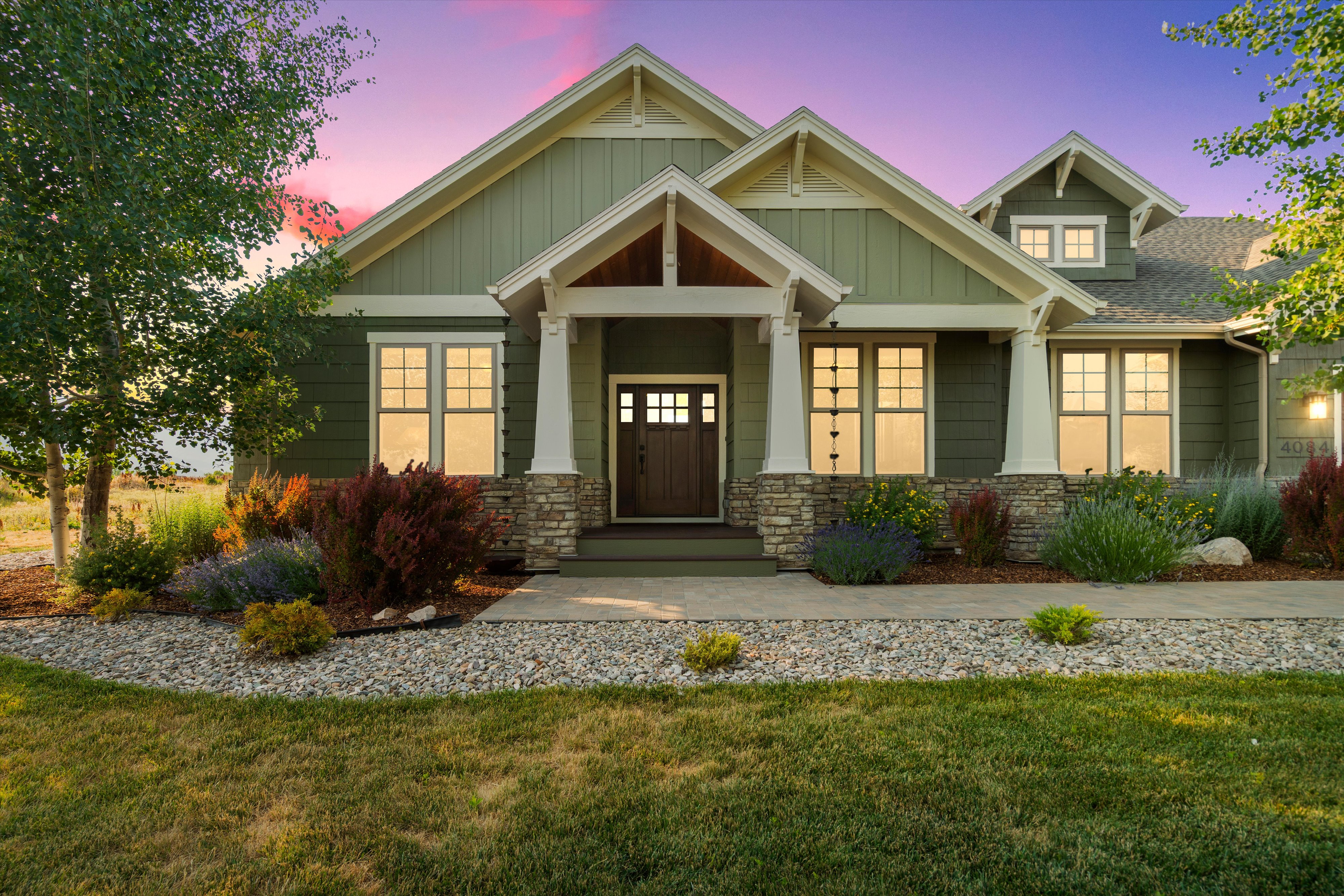 Craftsman-style exterior featuring a prominent gabled entrance with decorative columns and a stone base