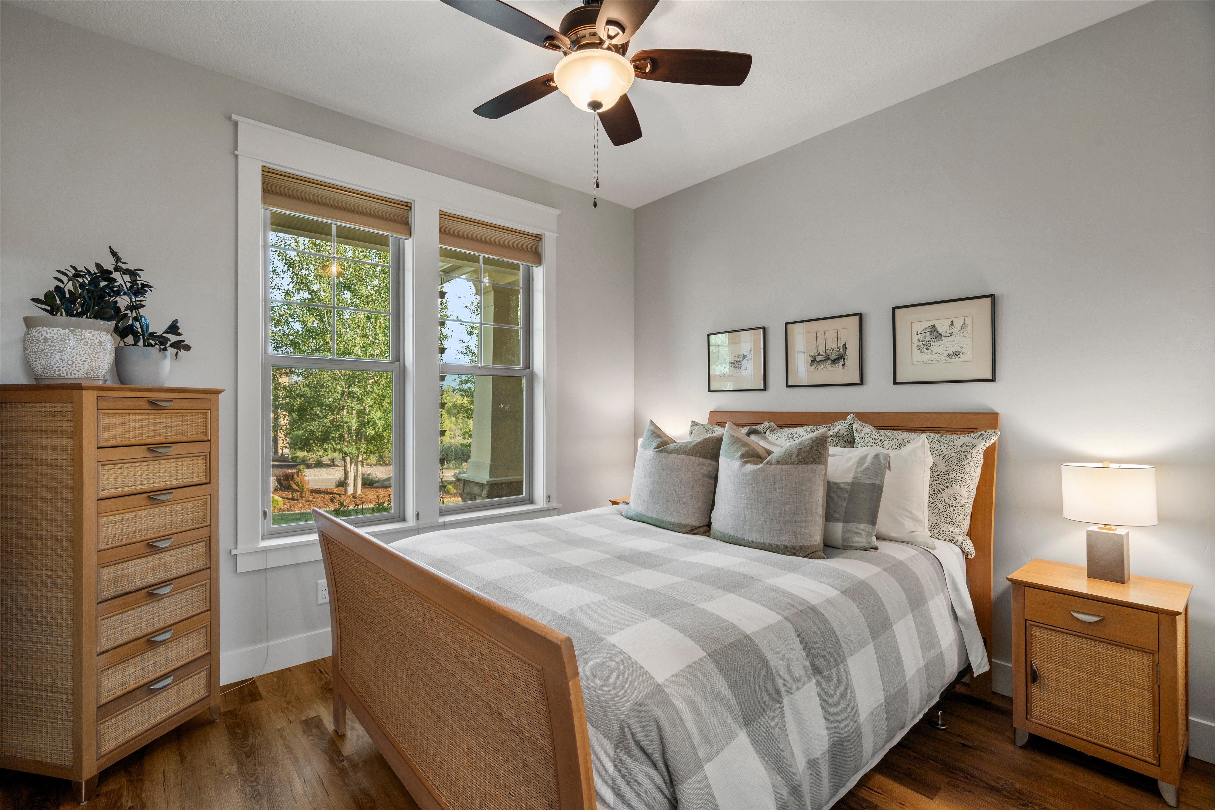 Bedroom featuring a ceiling fan, wood-finish flooring, two large windows with natural light, and classic white trim