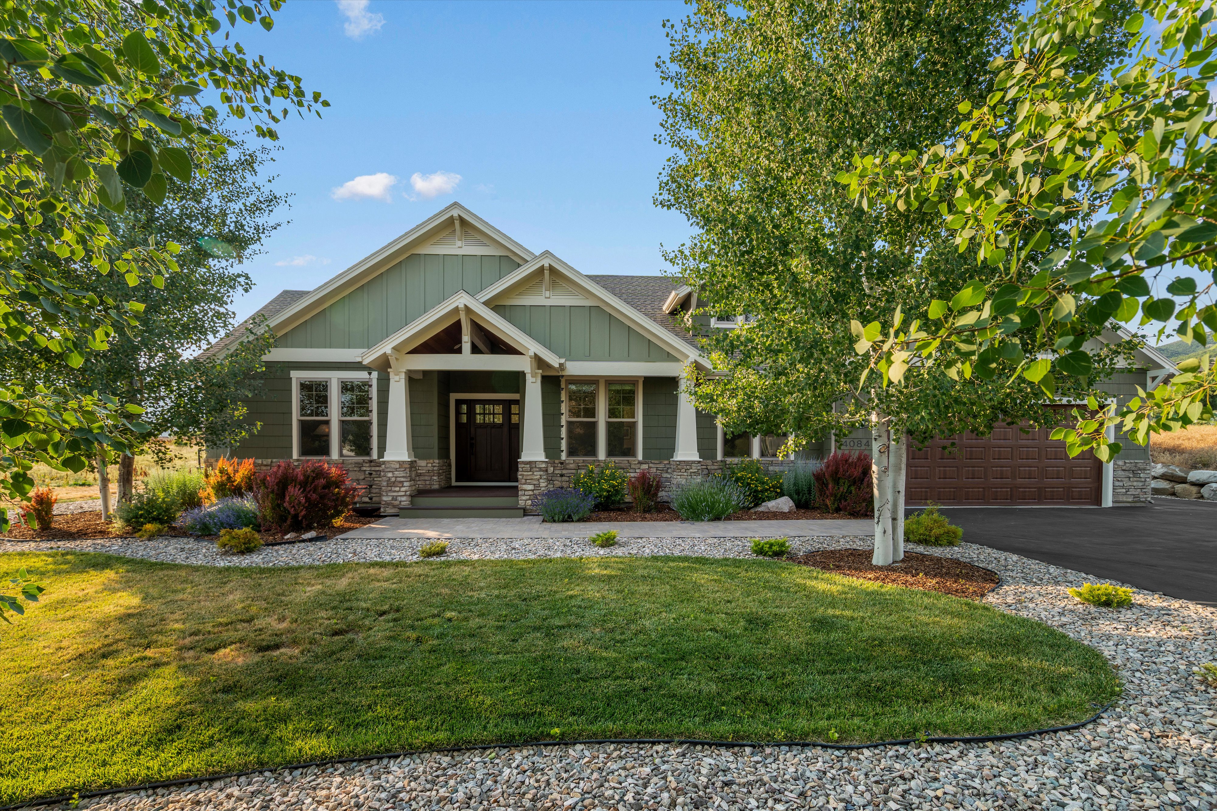 Craftsman-style exterior with green siding, stone accents, and a covered entry porch