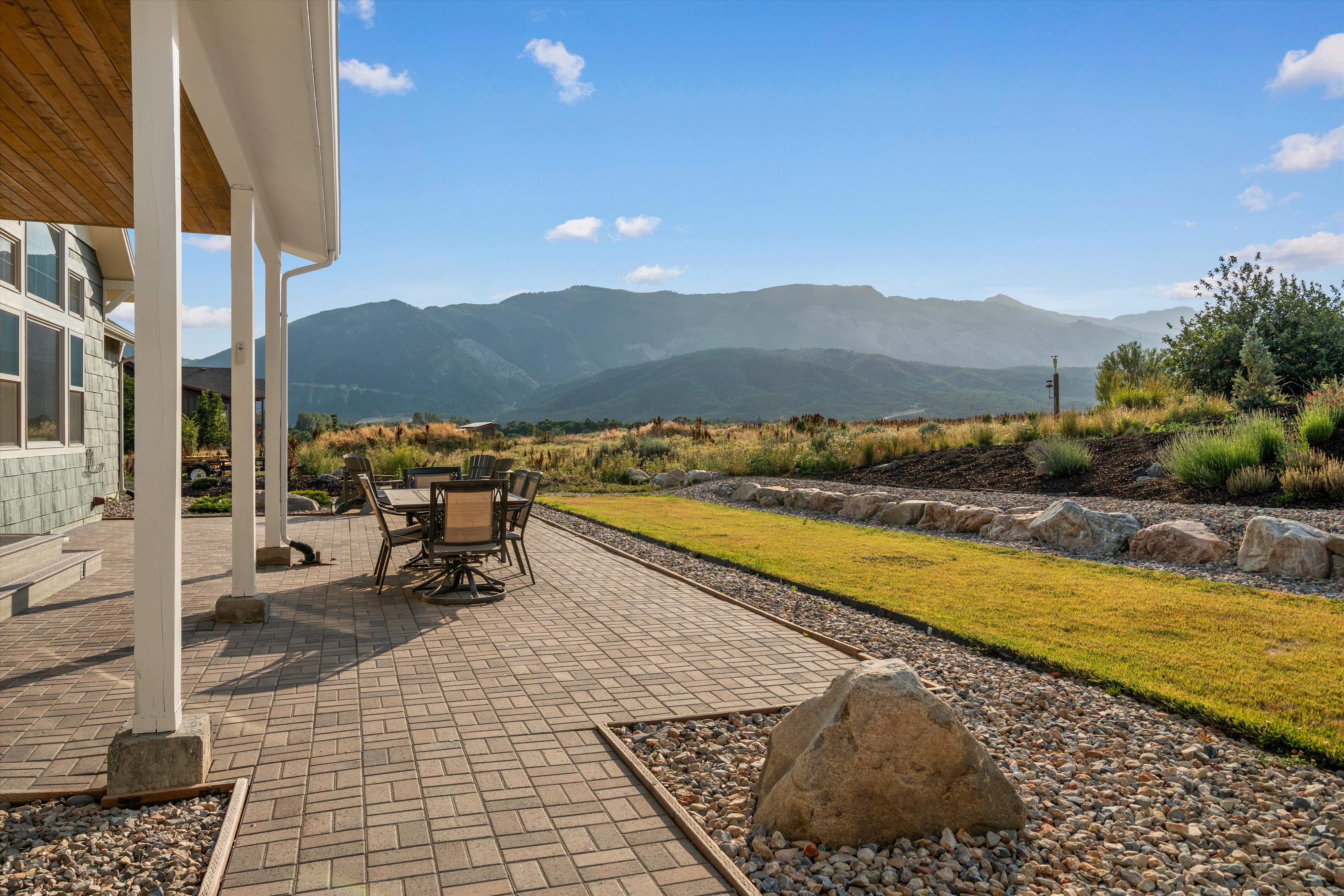 Expansive paver patio with covered porch, wood-finish ceiling, and mountain scenery