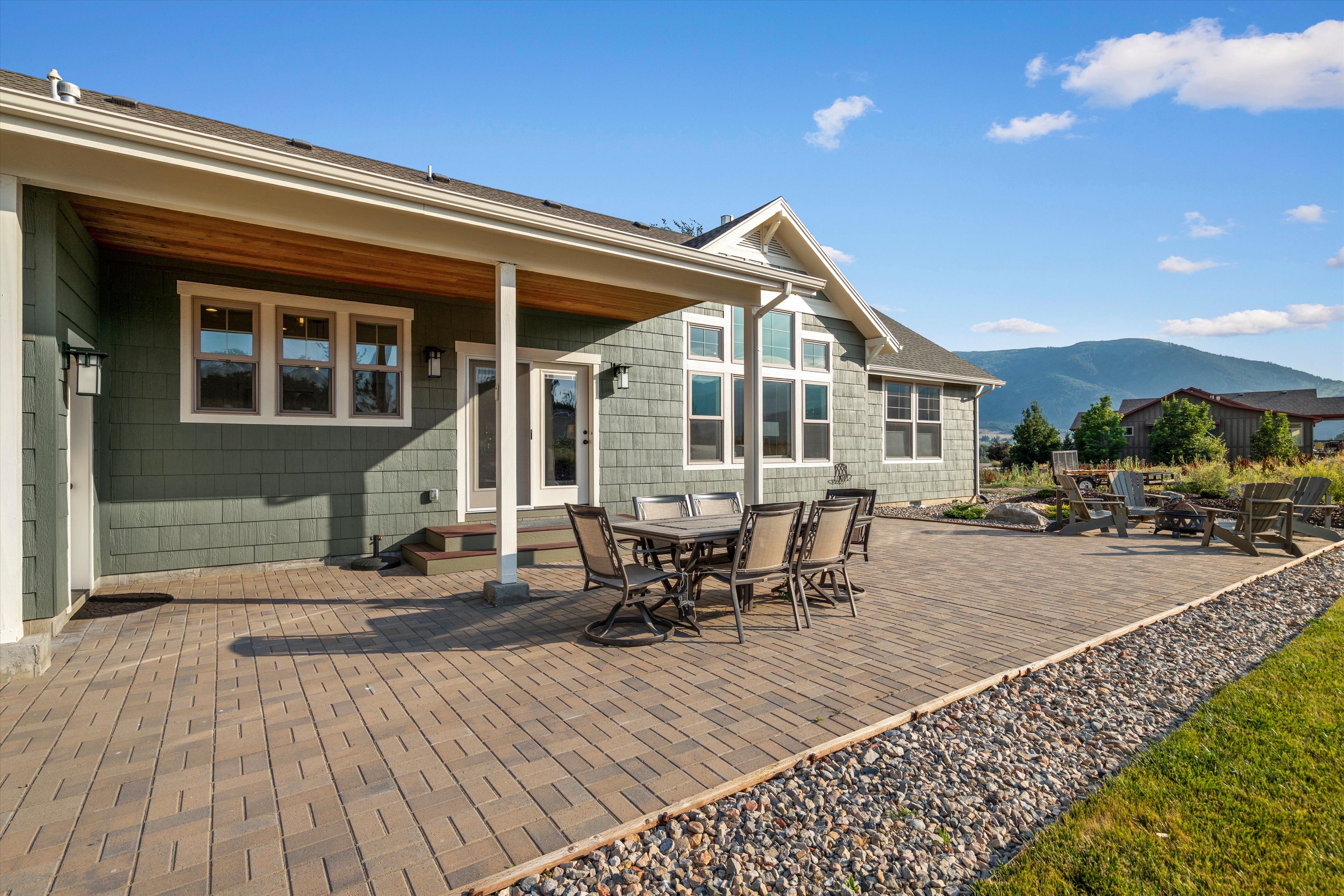 Expansive paver patio with a covered outdoor living area and a rock border
