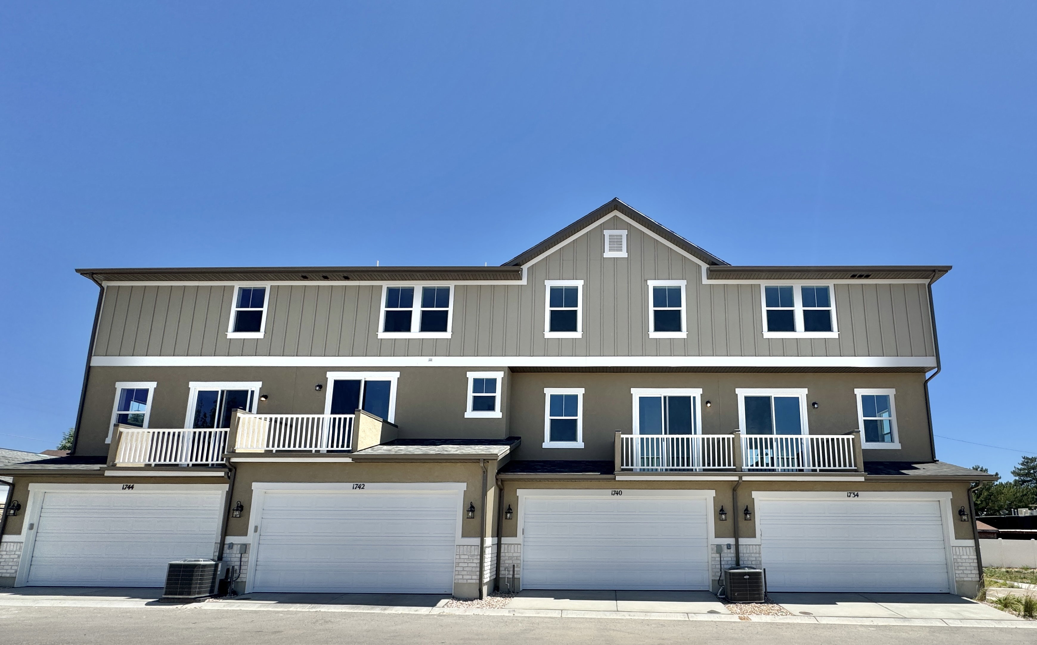 Multi-level townhome-style residences featuring individual garage access and private balconies with white railings