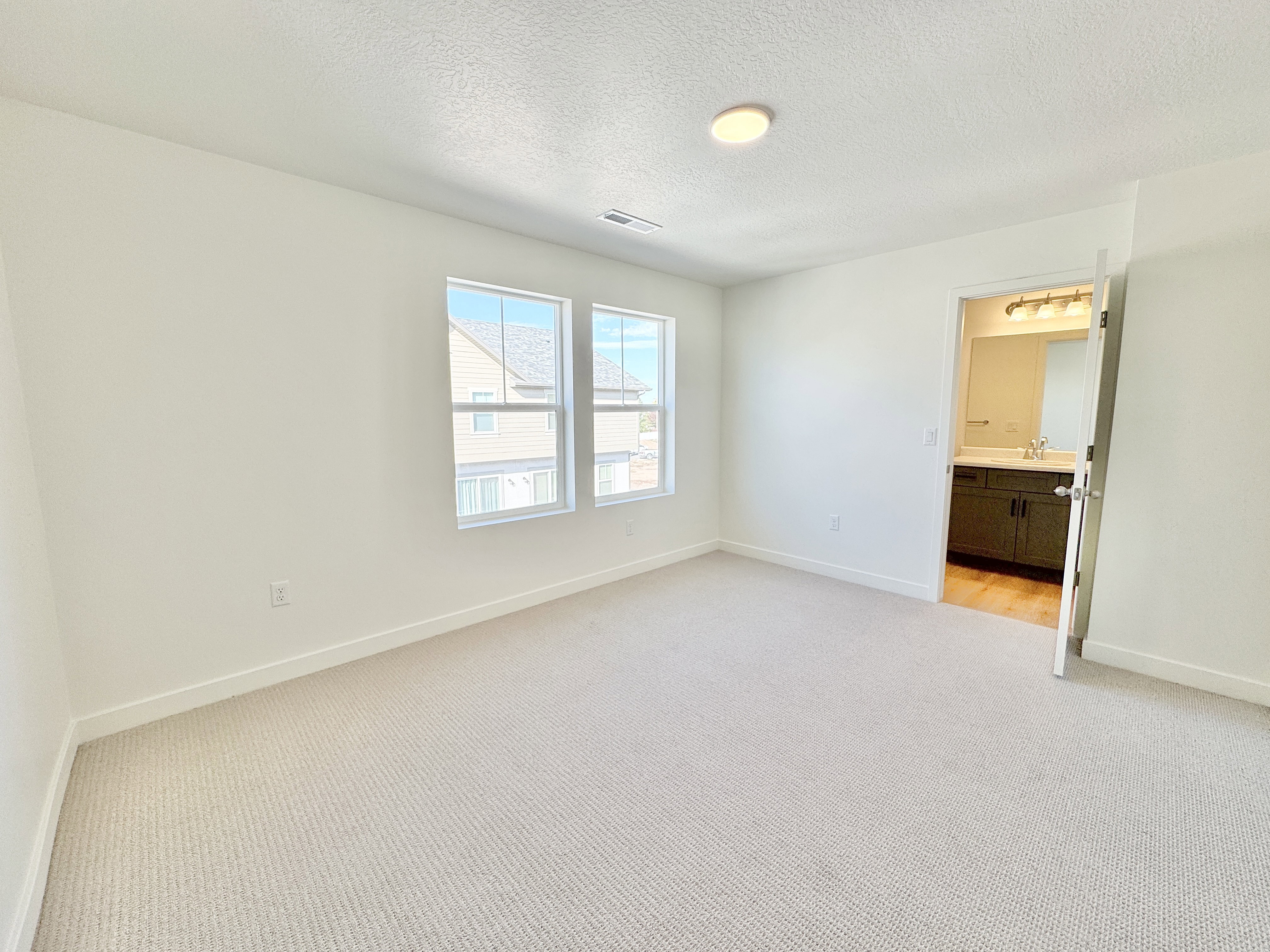 Room featuring light-toned carpet flooring, white walls, and a flat ceiling with a flush-mount light fixture