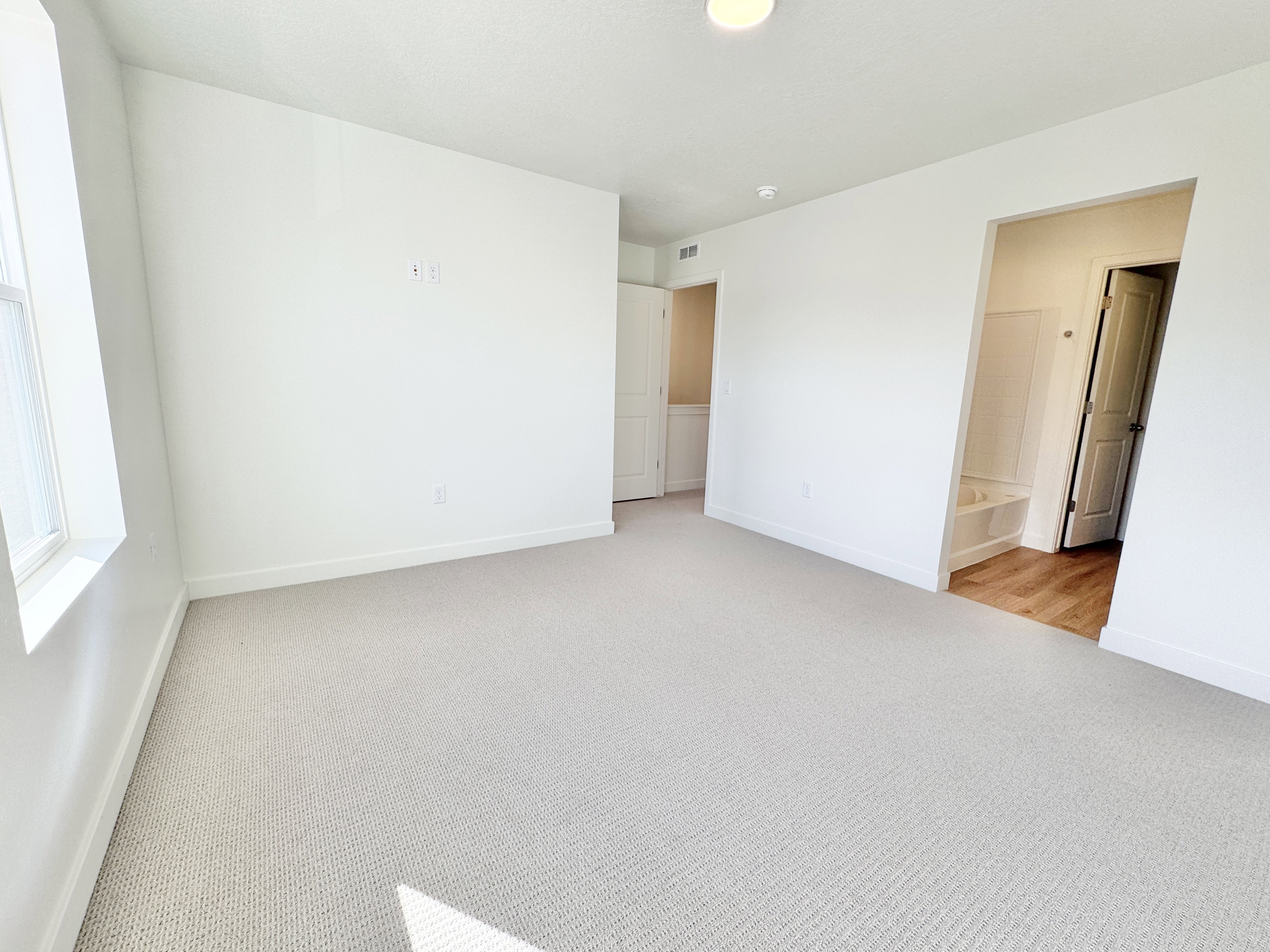 Spacious room featuring light-toned carpeting and a large window