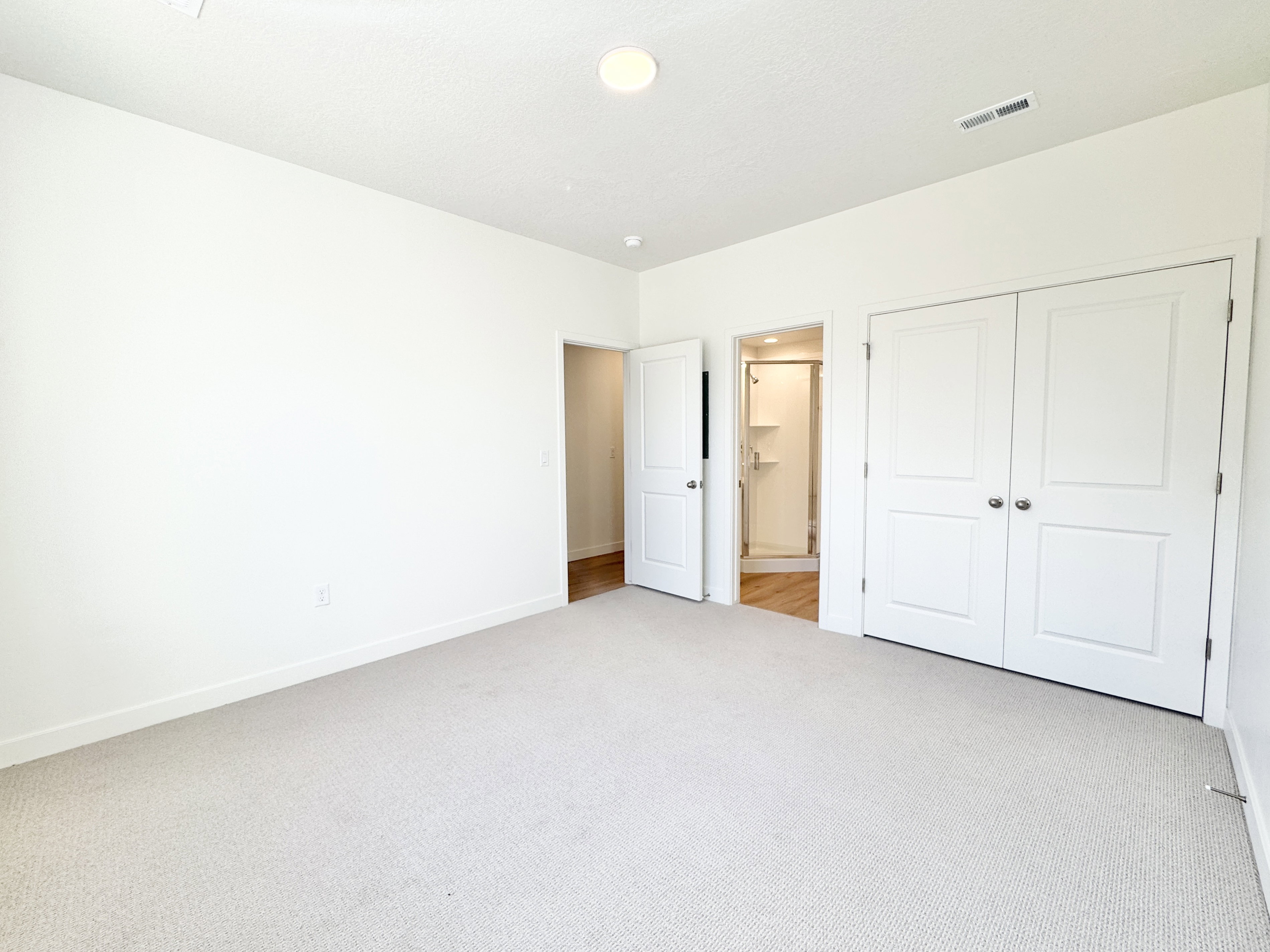 Spacious room with light-toned carpeting and white walls