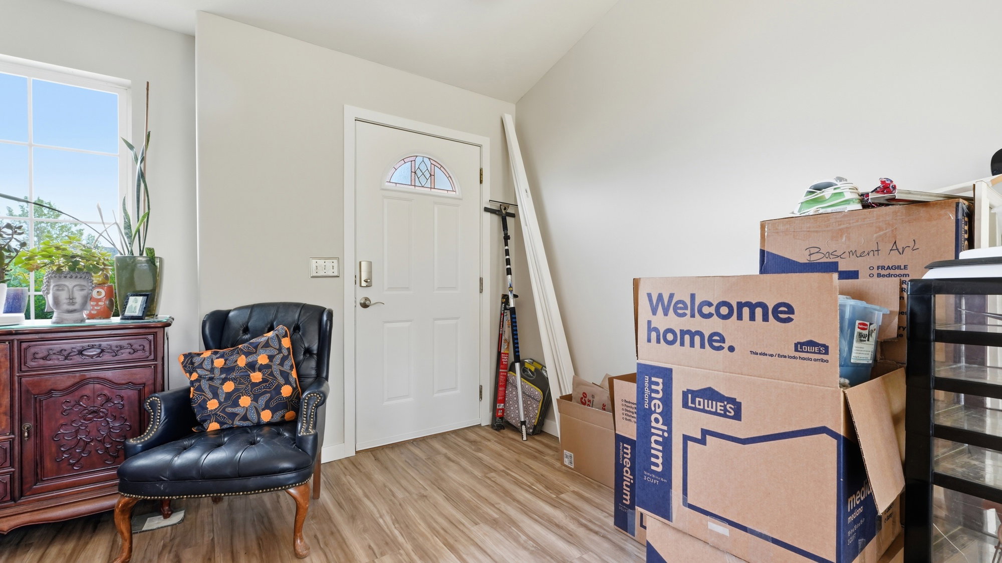 Entryway featuring LVP, a white paneled door with an arched decorative glass insert, and neutral wall paint