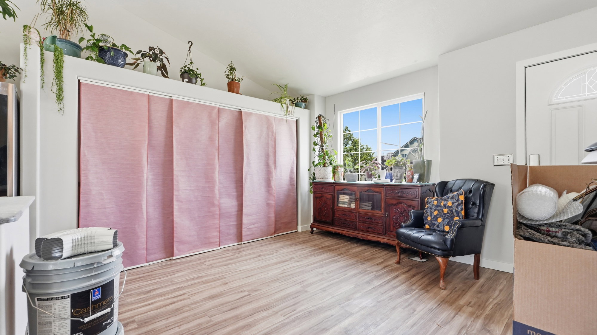 Interior space featuring light wood-finish flooring, a large window with natural light, and a white entry door