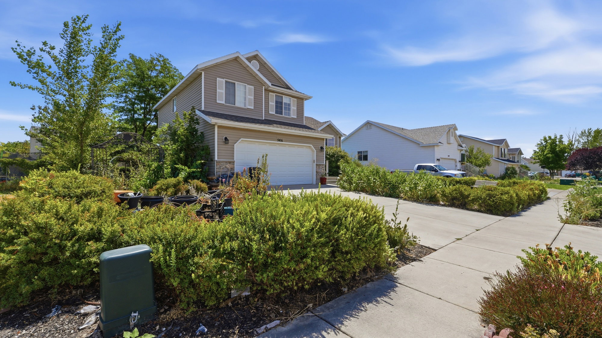 Two-story residence featuring siding and stone facade, an attached garage, and a concrete driveway