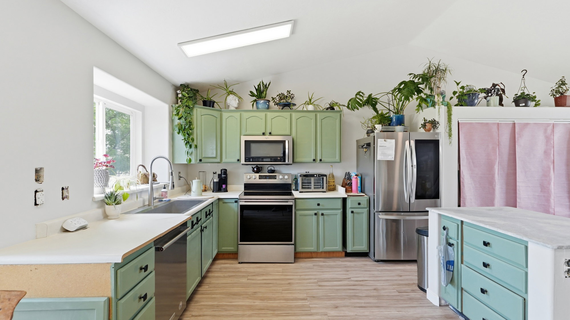 Kitchen featuring green cabinetry, stainless steel appliances, and wood-finish flooring