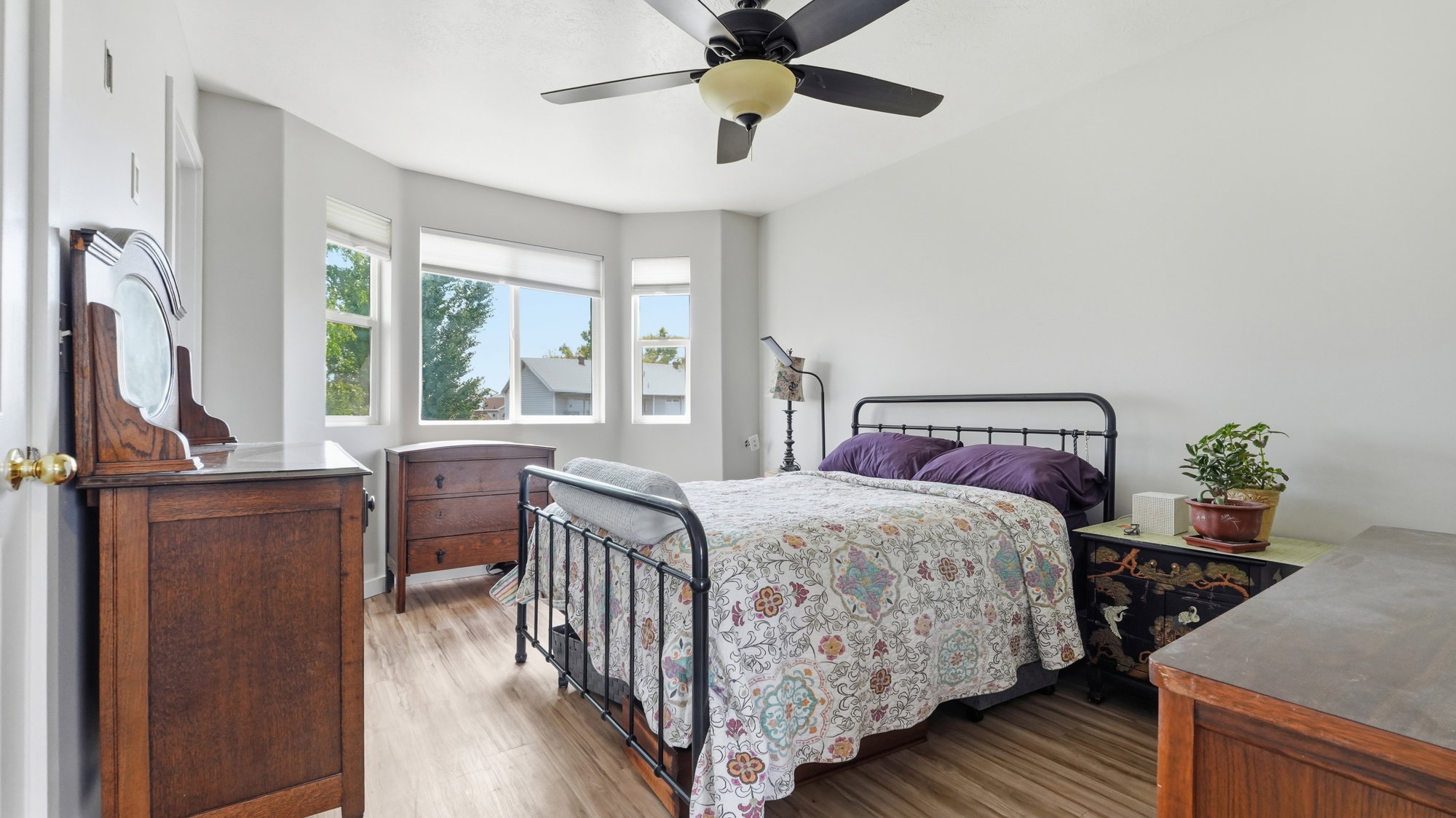 Primary bedroom Bay window with multiple windows, lvp flooring, and a ceiling fan