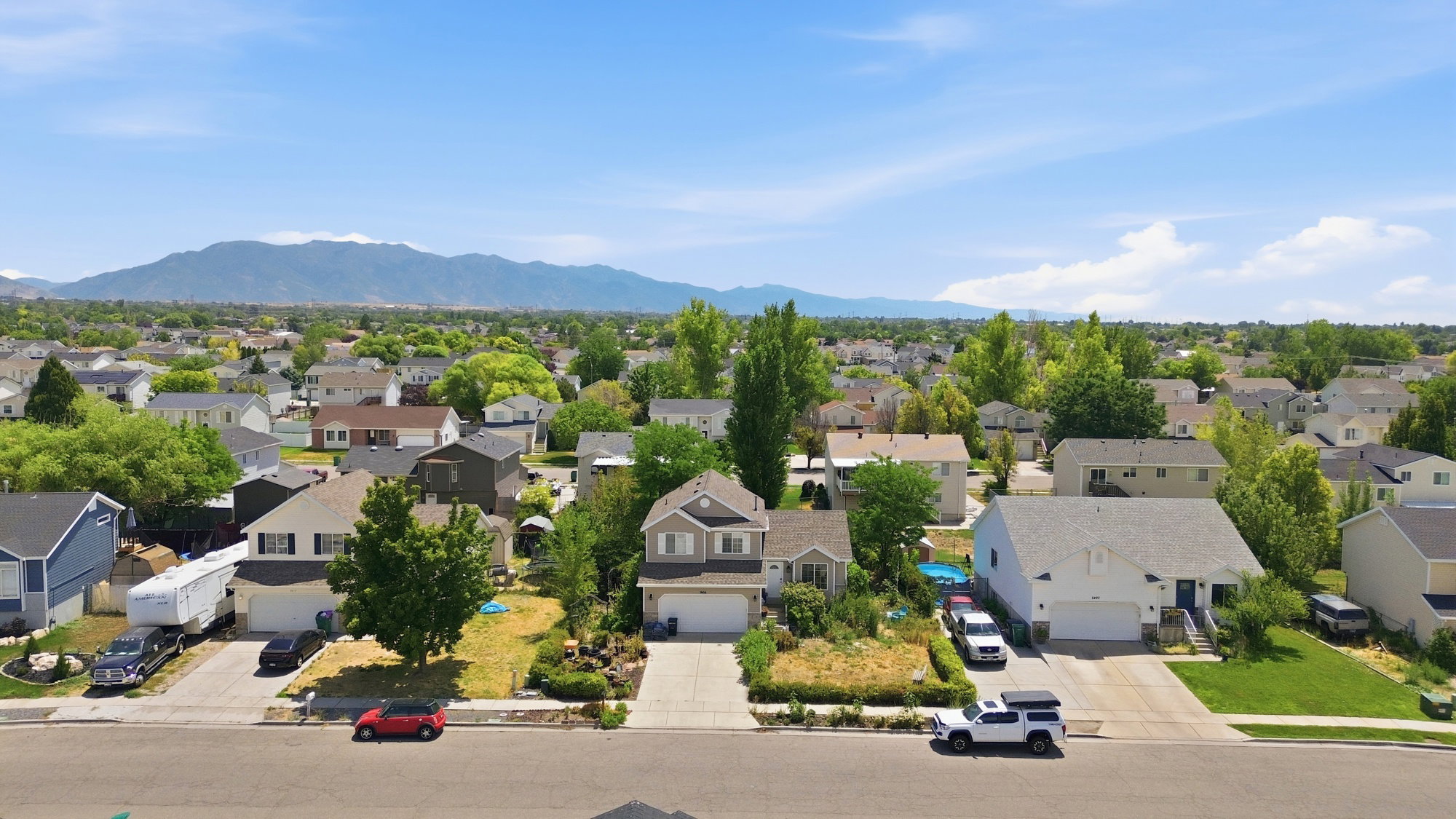 Residential neighborhood with mature trees, established landscaping, and mountain backdrop