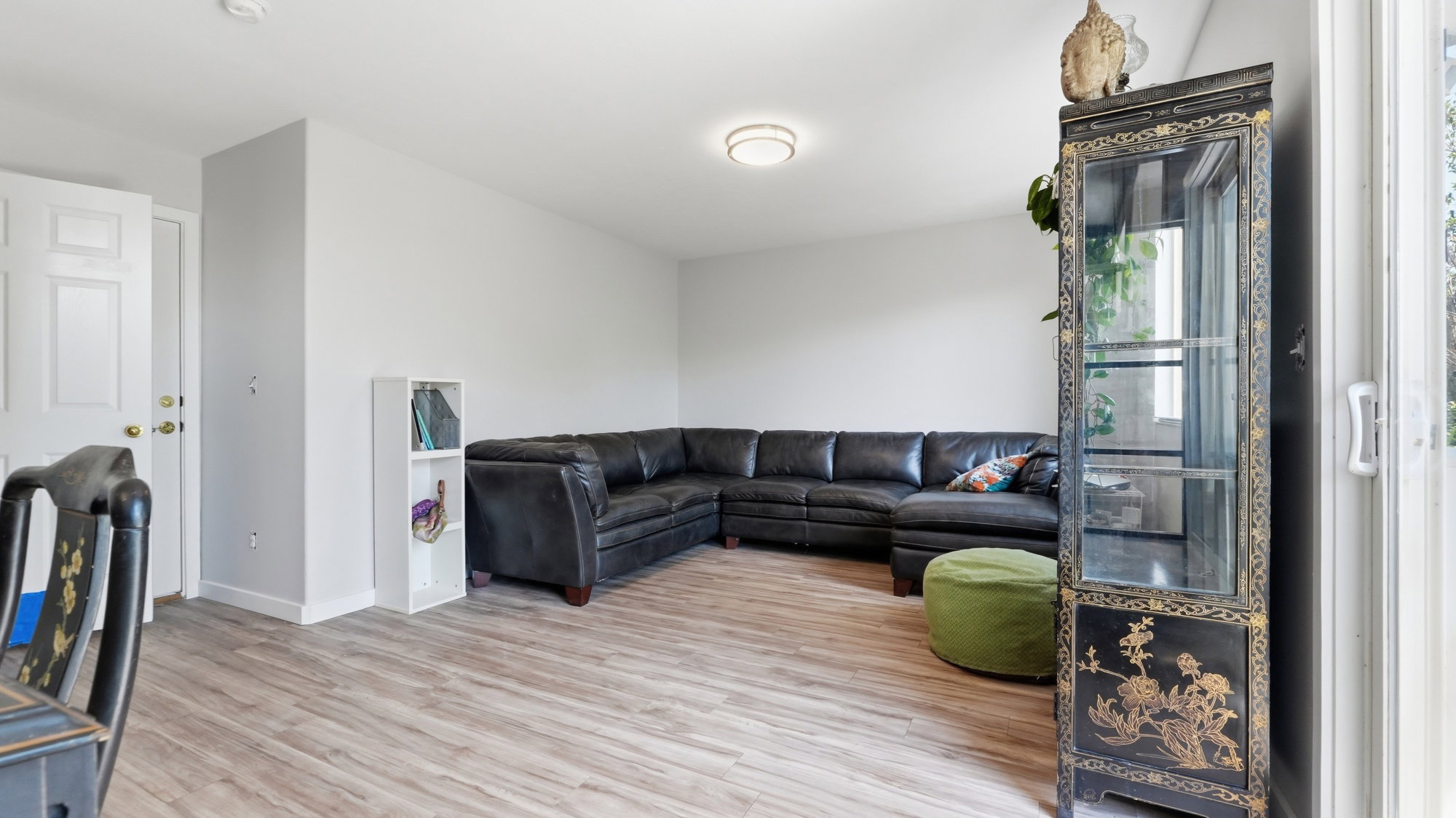 Open-concept living area with wood-finish flooring, light gray wall paint, and a white paneled door