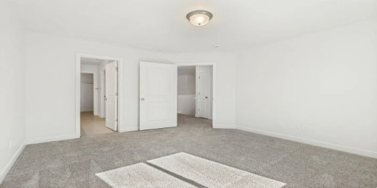 Spacious room featuring neutral carpeting and white painted walls. This home is under construction, the pictures are of a similar home